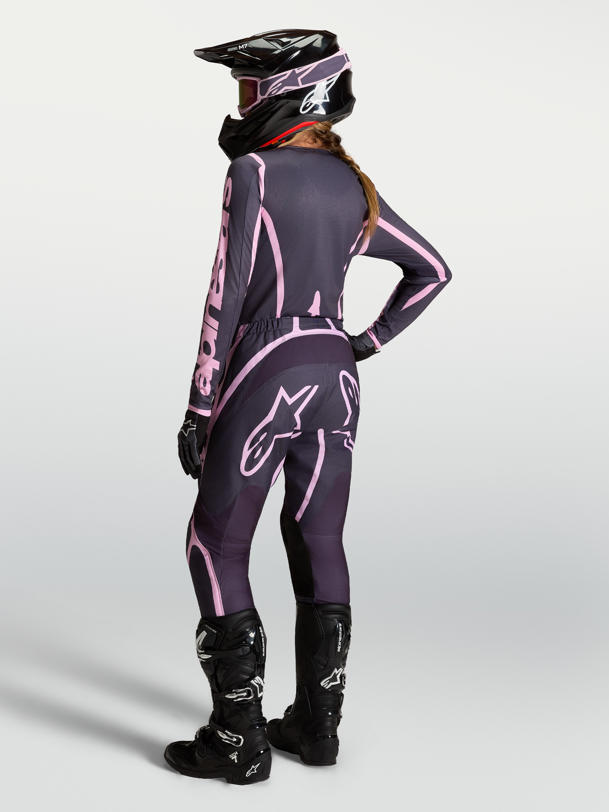 Alpinestars Maglia Stella Fluid Apex V2 AND Stella Fluid Apex V2 Gear Set, completo da motocross da donna, grigio e rosa, con stivali neri, modella vista di spalle