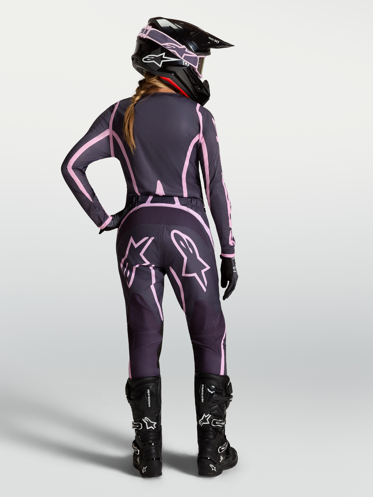 Alpinestars Pantaloni Stella Fluid Apex V2, pantaloni da motocross da donna, grigio e rosa, vista posteriore su modella con attrezzatura coordinata.