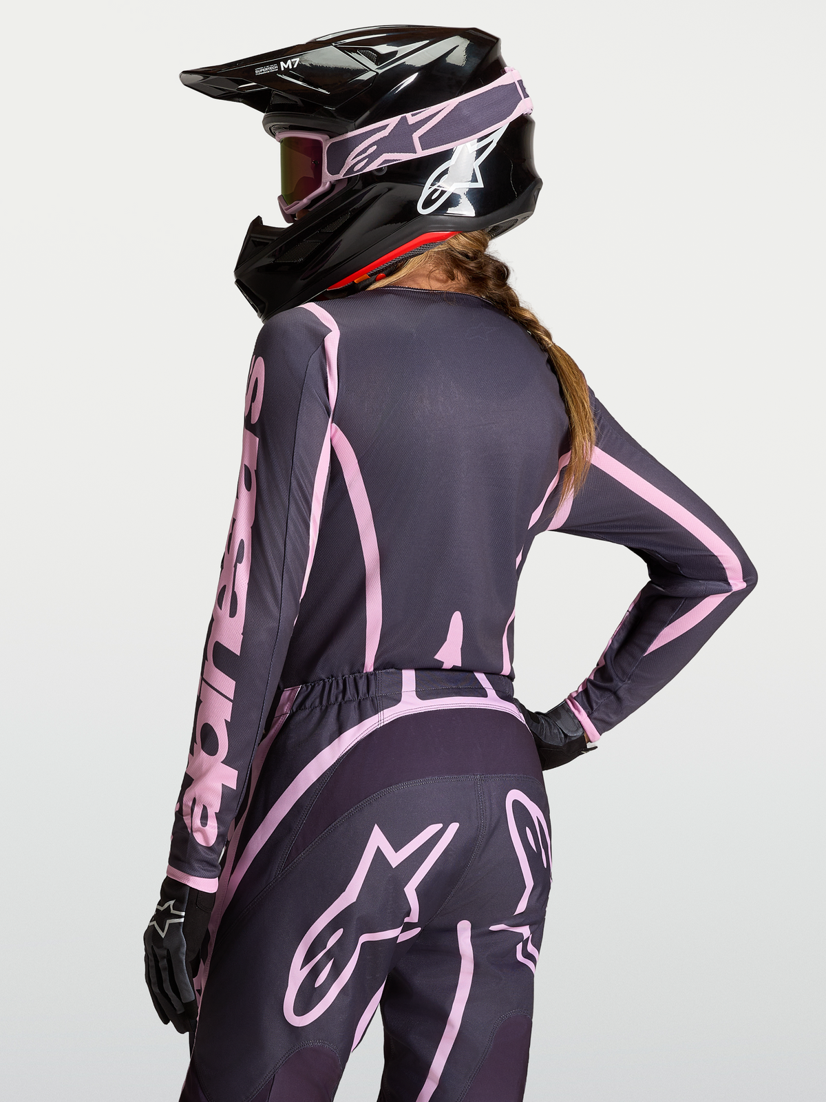 Maglia Stella Fluid Apex V2, maglia motocross da donna, colore grigio e rosa, indossata con casco nero coordinato.