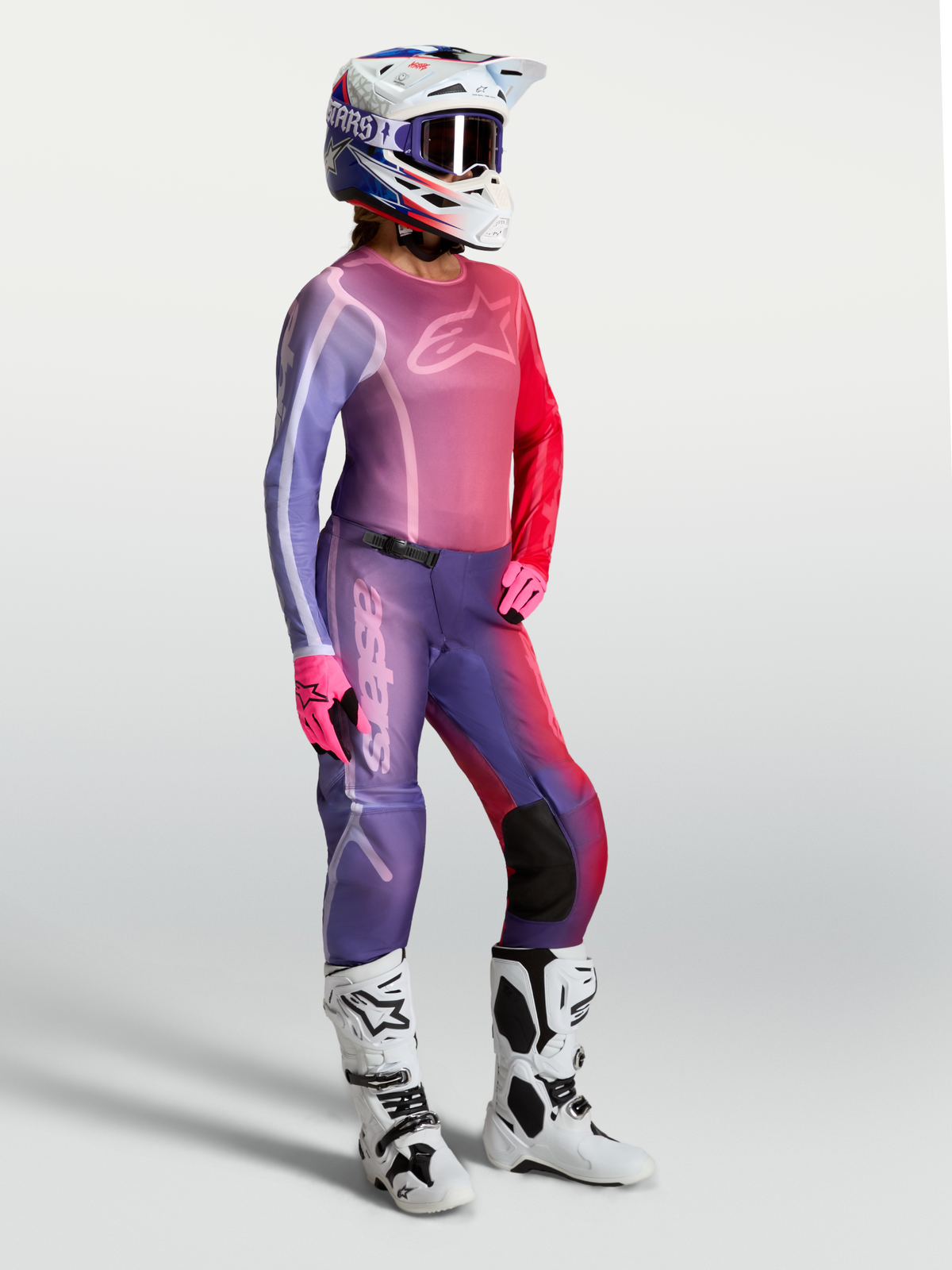 Alpinestars Maglia Stella Fluid Kepler, maglia da motocross per donna, viola e rossa, indossata con pantaloni coordinati e stivali bianchi, abbigliamento tecnico per fuoristrada e MX
