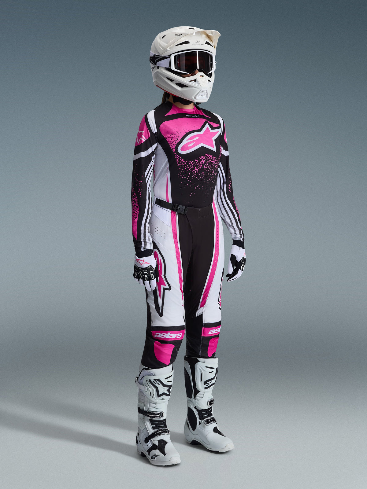 Alpinestars Stella Techstar Nomur Gear Set 2026, abbigliamento completo da motocross da donna, maglia rosa vivace, nera e bianca con pantaloni coordinati, casco e occhiali bianchi, stivali bianchi e neri, completo professionale da motocross coordinato