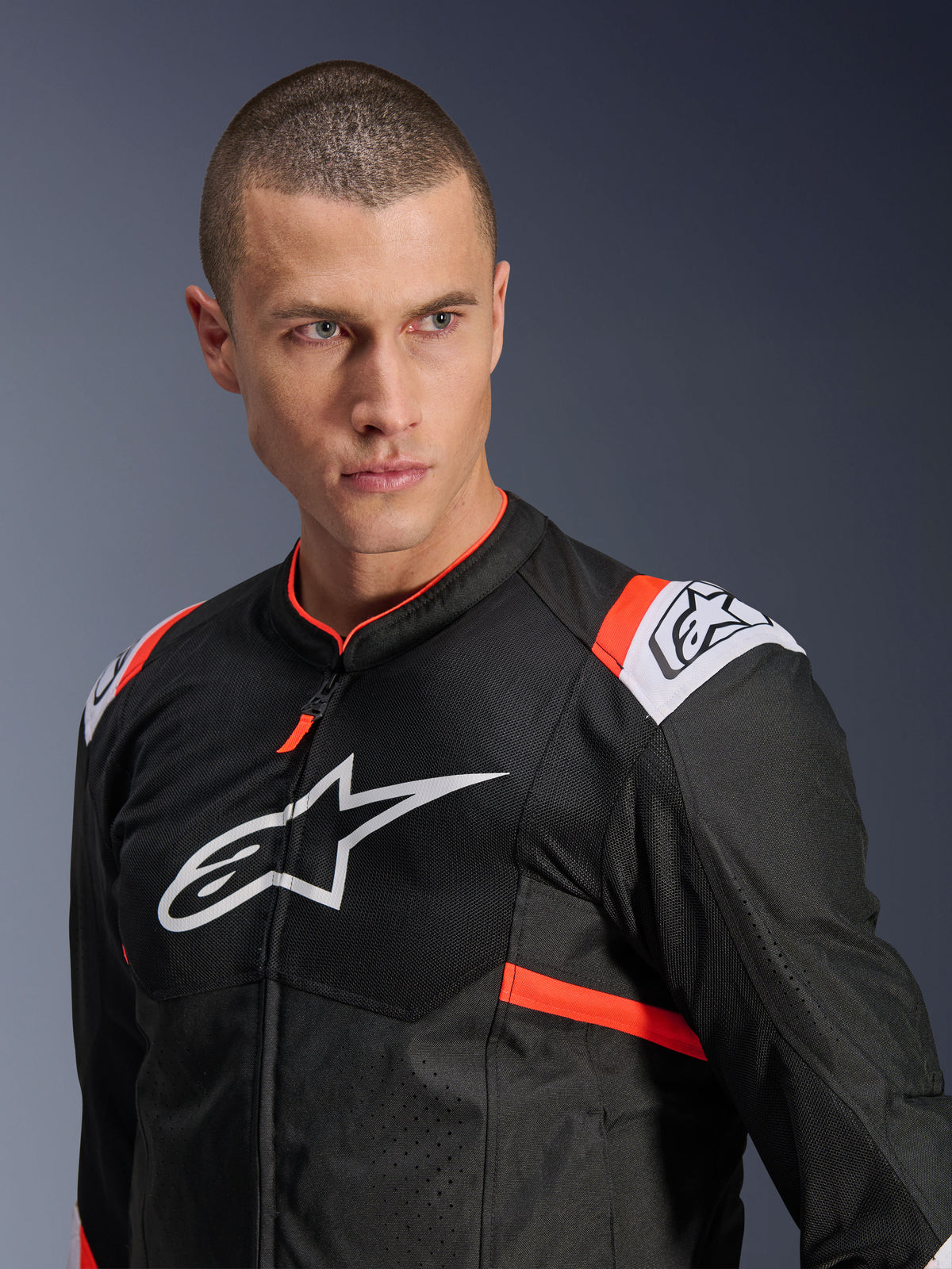Giacca Alpinestars T-SPS Air v2, nero con dettagli bianchi e rosso fluo, costruzione in tessuto mesh per il flusso d'aria, grande logo Alpinestars bianco sul petto, indossata da un modello, stile urban sport