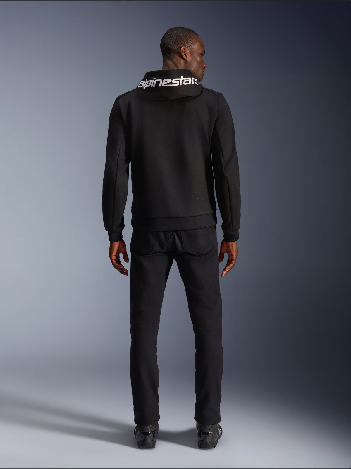 Alpinestars Chrome V2 Sport Hoodie, felpa da moto in pile tecnico nero con logo bianco sul cappuccio, vista posteriore su modello.