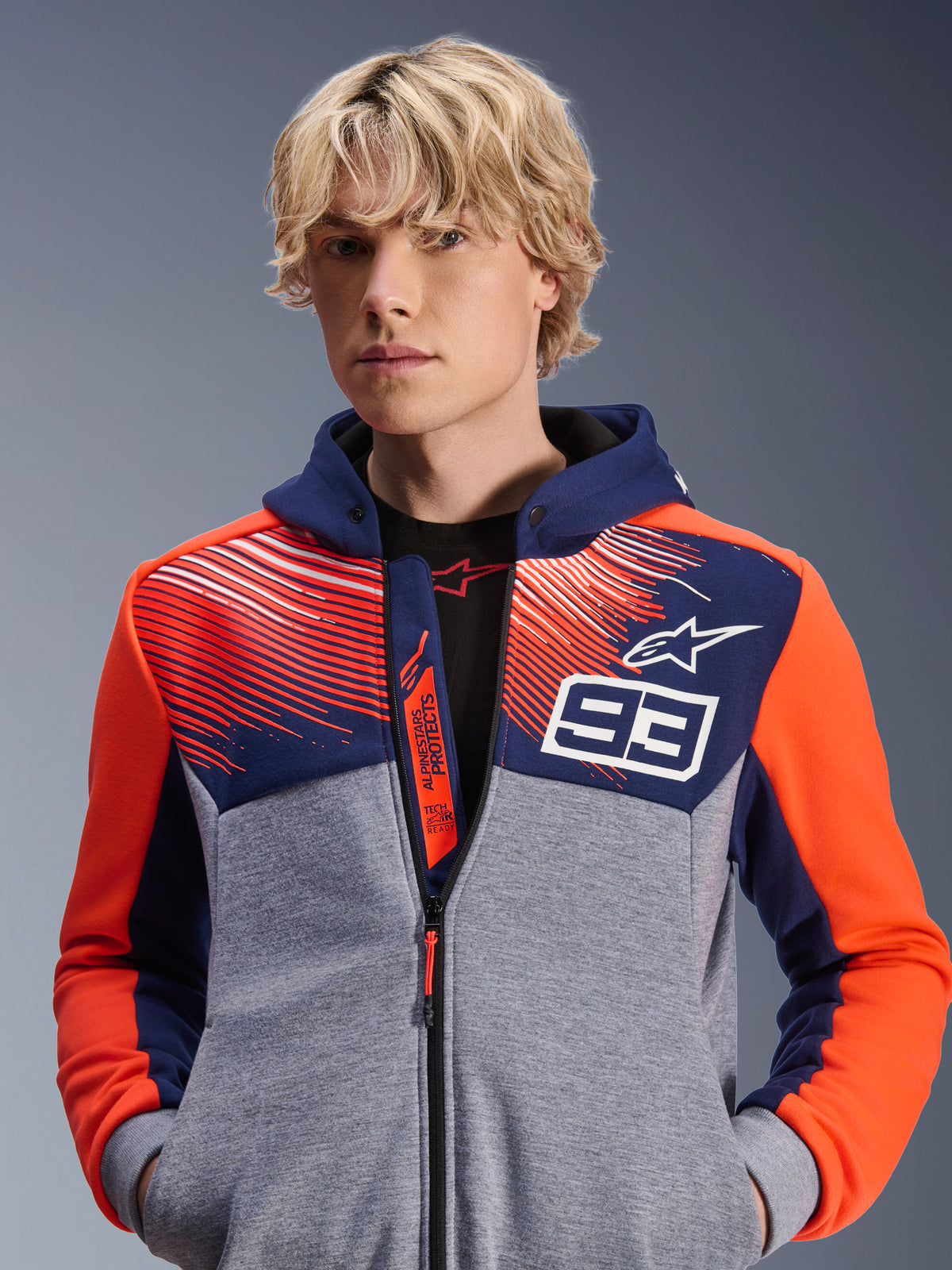 Alpinestars MM93 Chrome V2 Sport Hoodie, felpa da moto urban, blu navy e grigio melange con accenti rosso fluo, con marchio Marc Marquez 93 e logo Alpinestars, design con zip intera, abbigliamento lifestyle casual per motociclisti