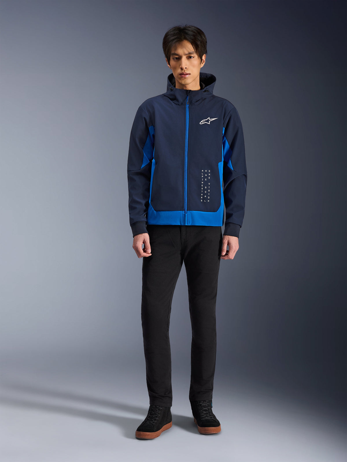 Alpinestars Radium Tech Hoodie, felpa da moto urbana in blu notte e blu reale, guscio tecnico antivento, design streetwear casual indossata con pantaloni neri e sneakers alte, con logo bianco sul petto