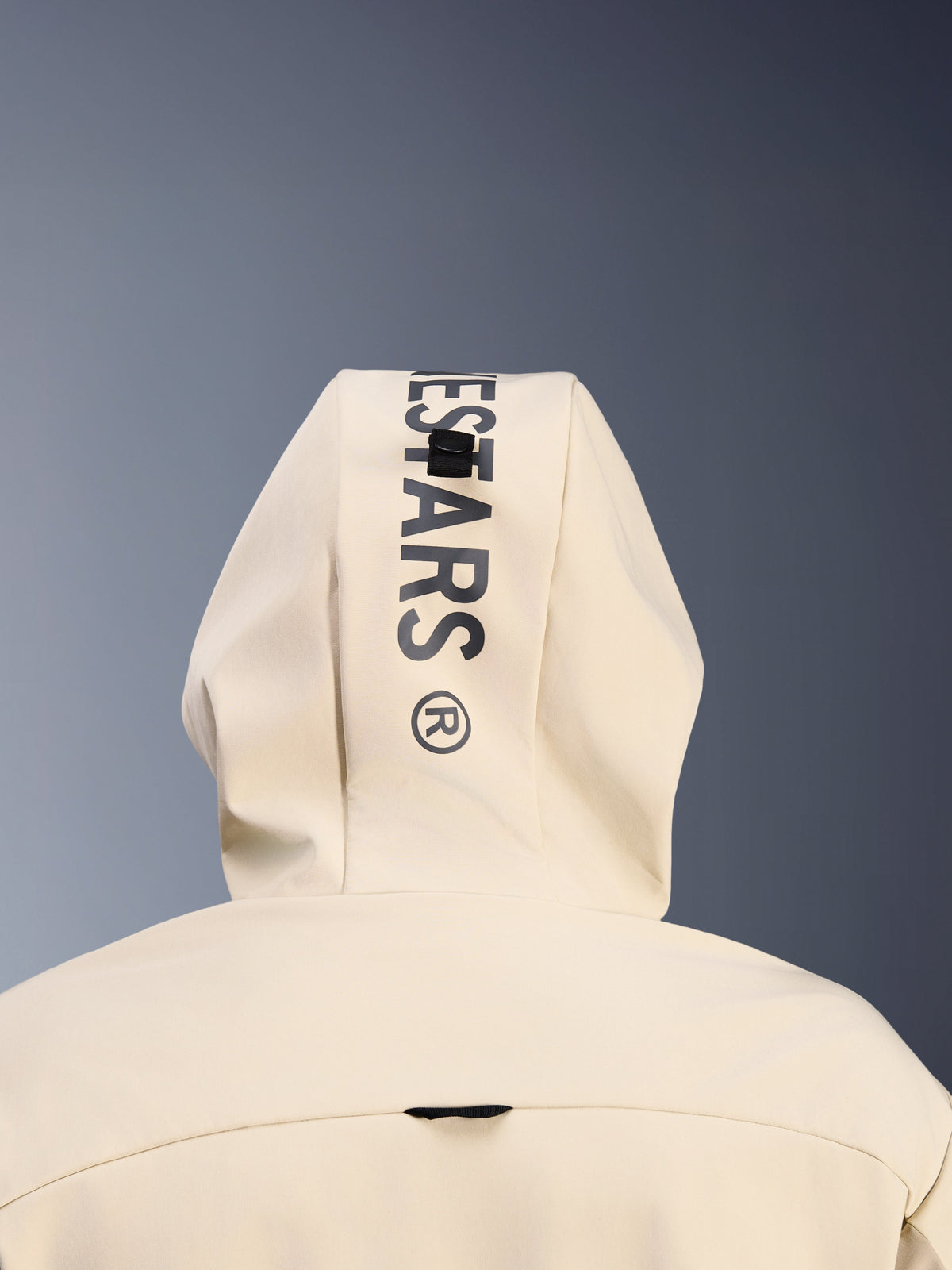 Alpinestars Radium Tech Hoodie in Mastic Aluminum, vista ravvicinata posteriore del cappuccio che mostra il marchio Alpinestars nero in verticale e il sistema ad asola per l'aggancio del cappuccio, dettaglio abbigliamento moto urban