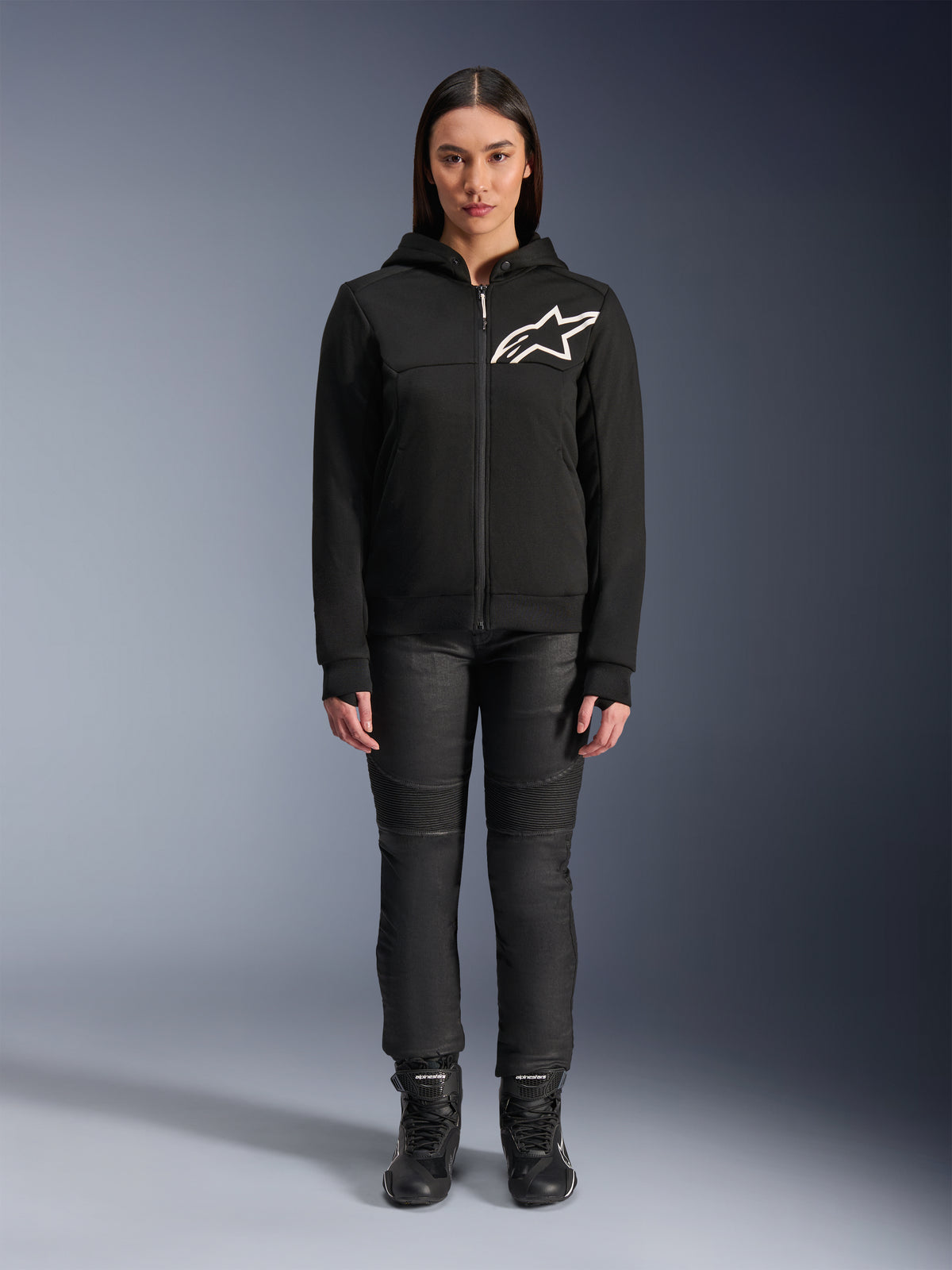 Alpinestars Stella Chrome V2 Sport Hoodie da donna, nera con logo Astars bianco sul petto, abbinata a pantaloni tecnici da guida e stivali neri, design di abbigliamento moto urbano