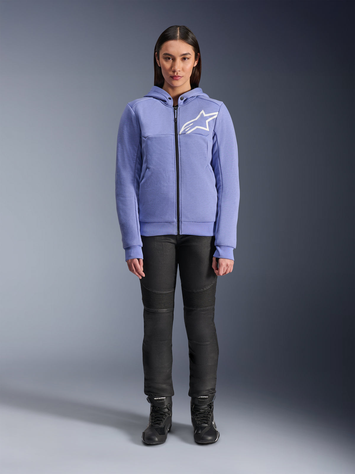 Alpinestars Stella Chrome V2 Sport Hoodie Donna, blu violetto con logo Astars bianco sul petto, felpa tecnica con zip intera e cappuccio, indossata con pantaloni da moto neri e stivali da guida, abbigliamento urban casual per motocicliste
