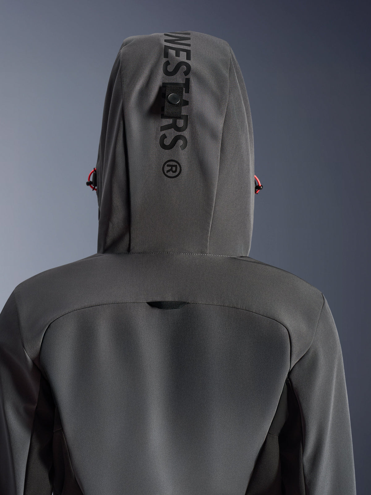 Alpinestars Stella Radium Tech Hoodie da donna, Deep Gray Black, vista posteriore ravvicinata del cappuccio con branding verticale e asola di fissaggio, dettagli dei cordini rossi, resistente costruzione in tessuto tecnico a 3 strati antivento per la guida motociclistica urbana.