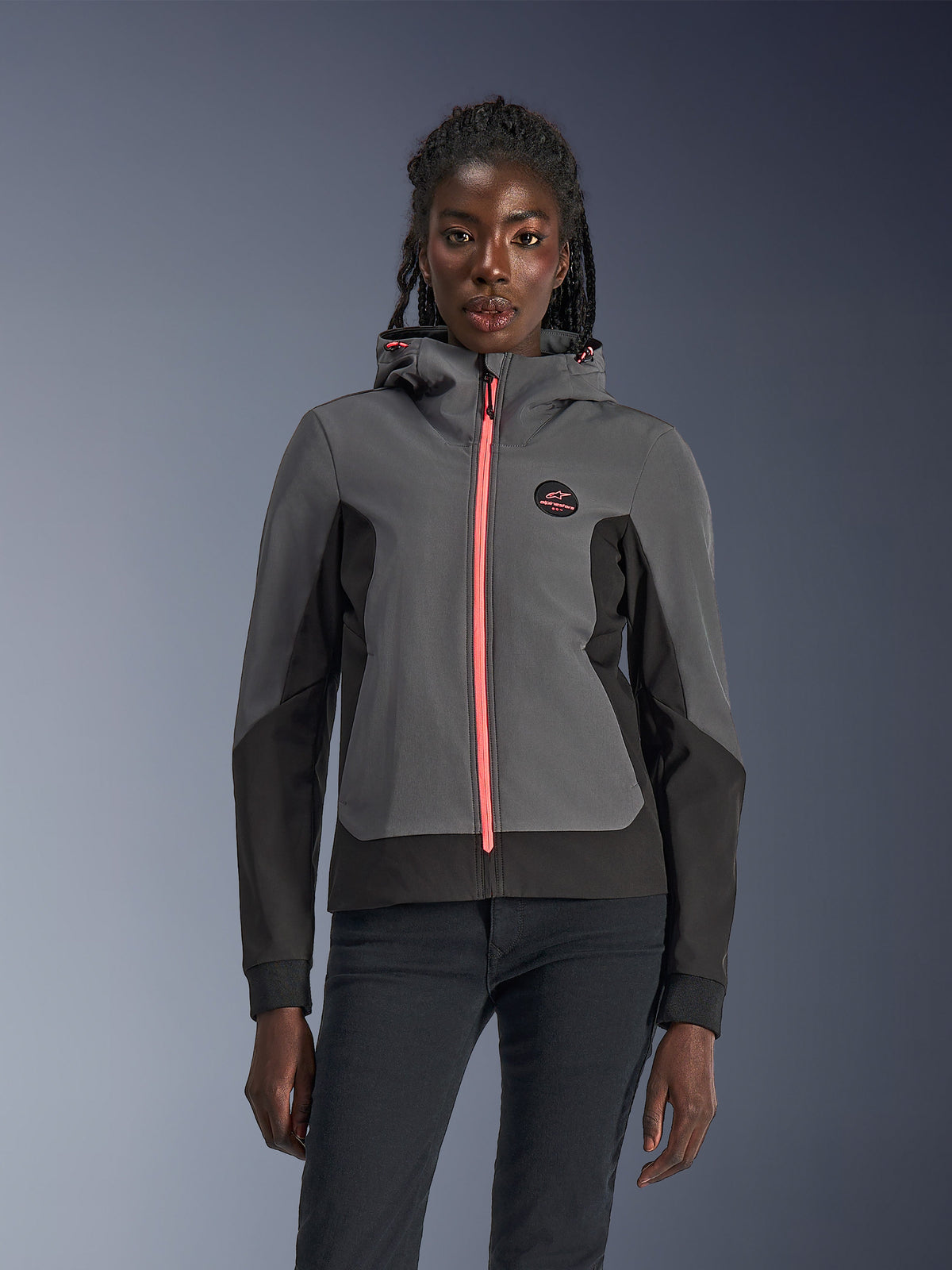 Alpinestars Stella Radium Tech Hoodie, felpa da moto da donna, grigio scuro e nero con zip e cordini del cappuccio rosa acceso, indossata da una modella, design urbano sportivo con logo Alpinestars sul petto