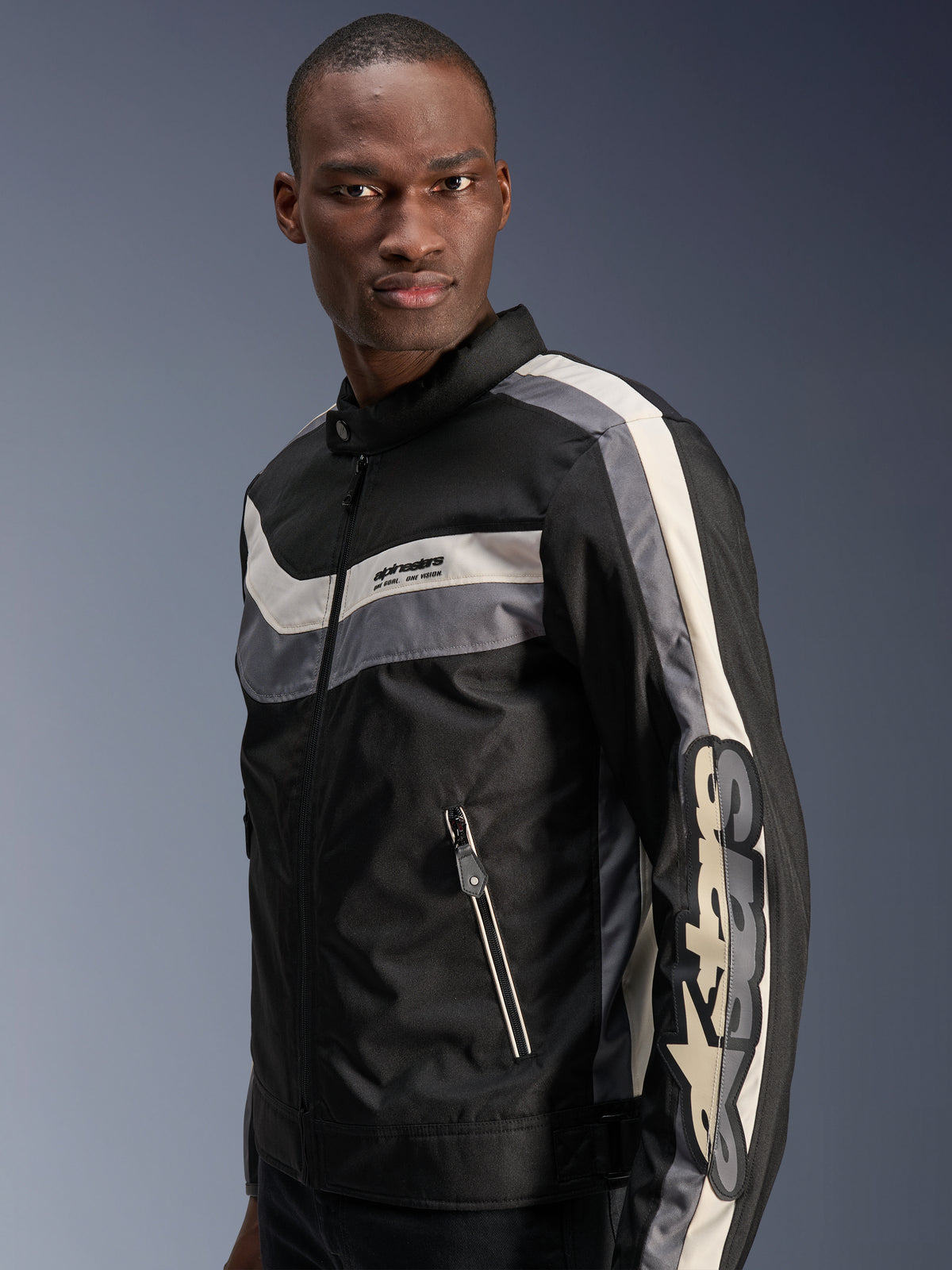 Giacca Alpinestars T-Dyno WR, Nero, Grigio Scuro ed Ecru, giacca da moto in tessuto d'ispirazione vintage con strisce orizzontali sul petto, grande logo verticale sulla manica e tasche anteriori con cerniera, abbigliamento urban road