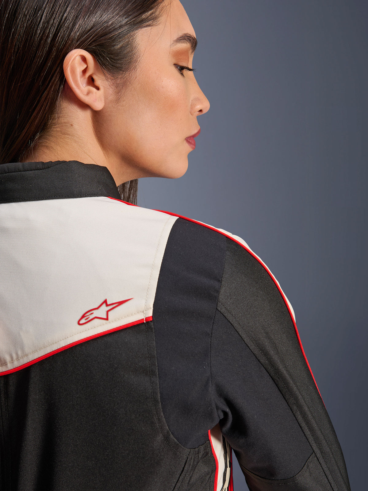 Giacca Alpinestars Stella T-Dyno WR in nero, ecru e rosso acceso, primo piano della spalla e della schiena, con pannelli ecru, profili rossi e logo a stella Alpinestars rosso, abbigliamento da moto in tessuto per donna