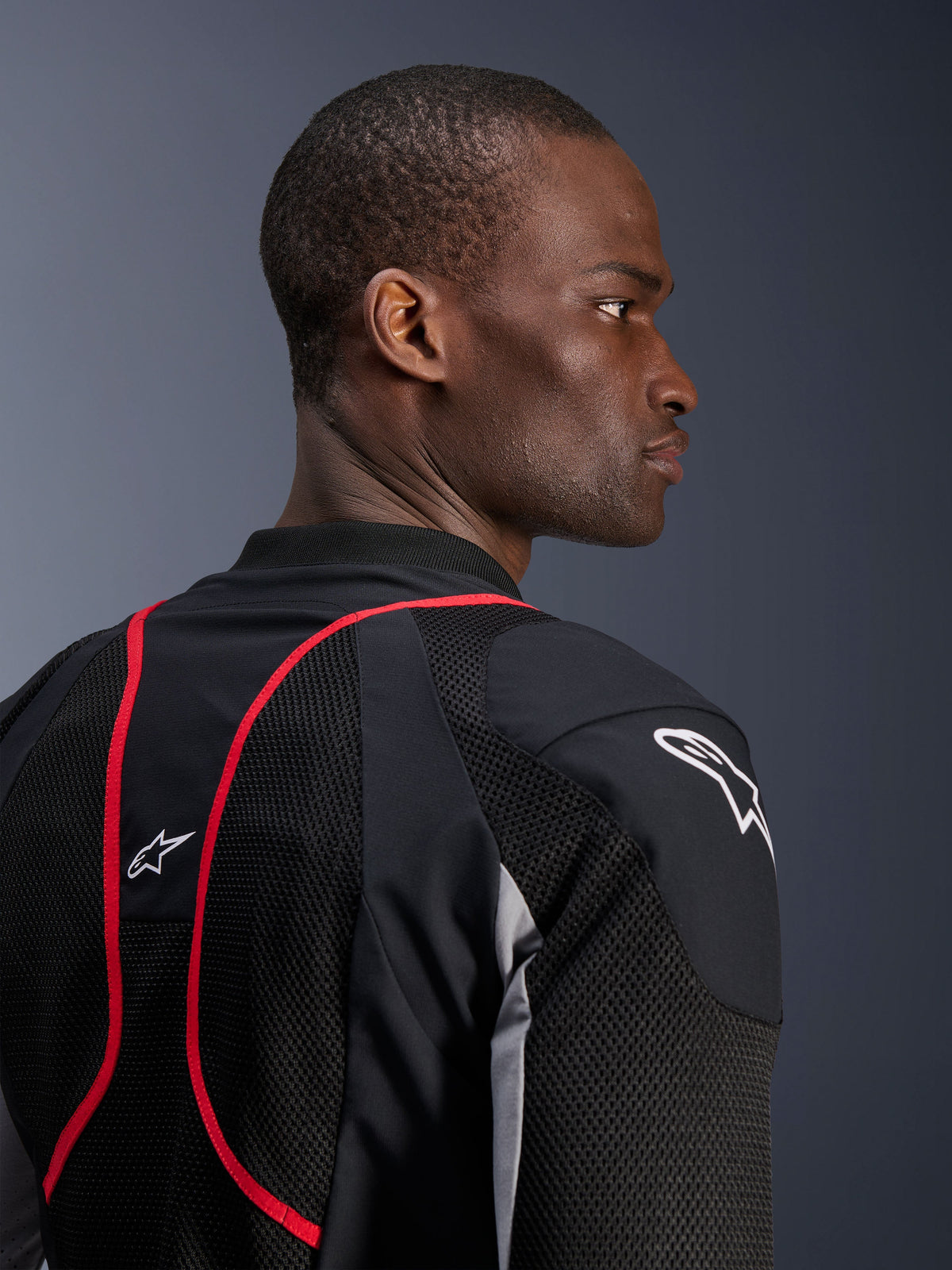 Giacca Alpinestars Troop-Air Pro, giacca tecnica corazzata, Nero Grigio Cenere e Rosso Brillante, vista ravvicinata di profilo e posteriore che mostra i pannelli in tessuto mesh, dettagli profilati rossi e loghi Astars bianchi sulla spalla e sulla parte superiore della schiena