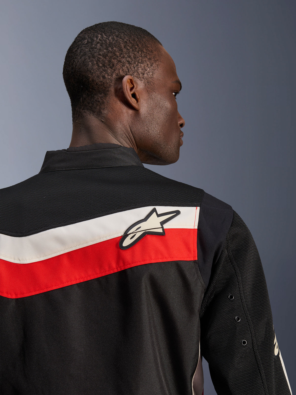 Giacca Alpinestars T-Dyno Air, Nero Rosso Brillante Ecru, vista ravvicinata della parte superiore della schiena e della spalla, caratterizzata da strisce orizzontali rosse ed ecru con logo Astars bianco, pannelli in mesh 3D traspirante sullo sprone e sulle maniche, giacca da moto in tessuto dallo stile classico moderno