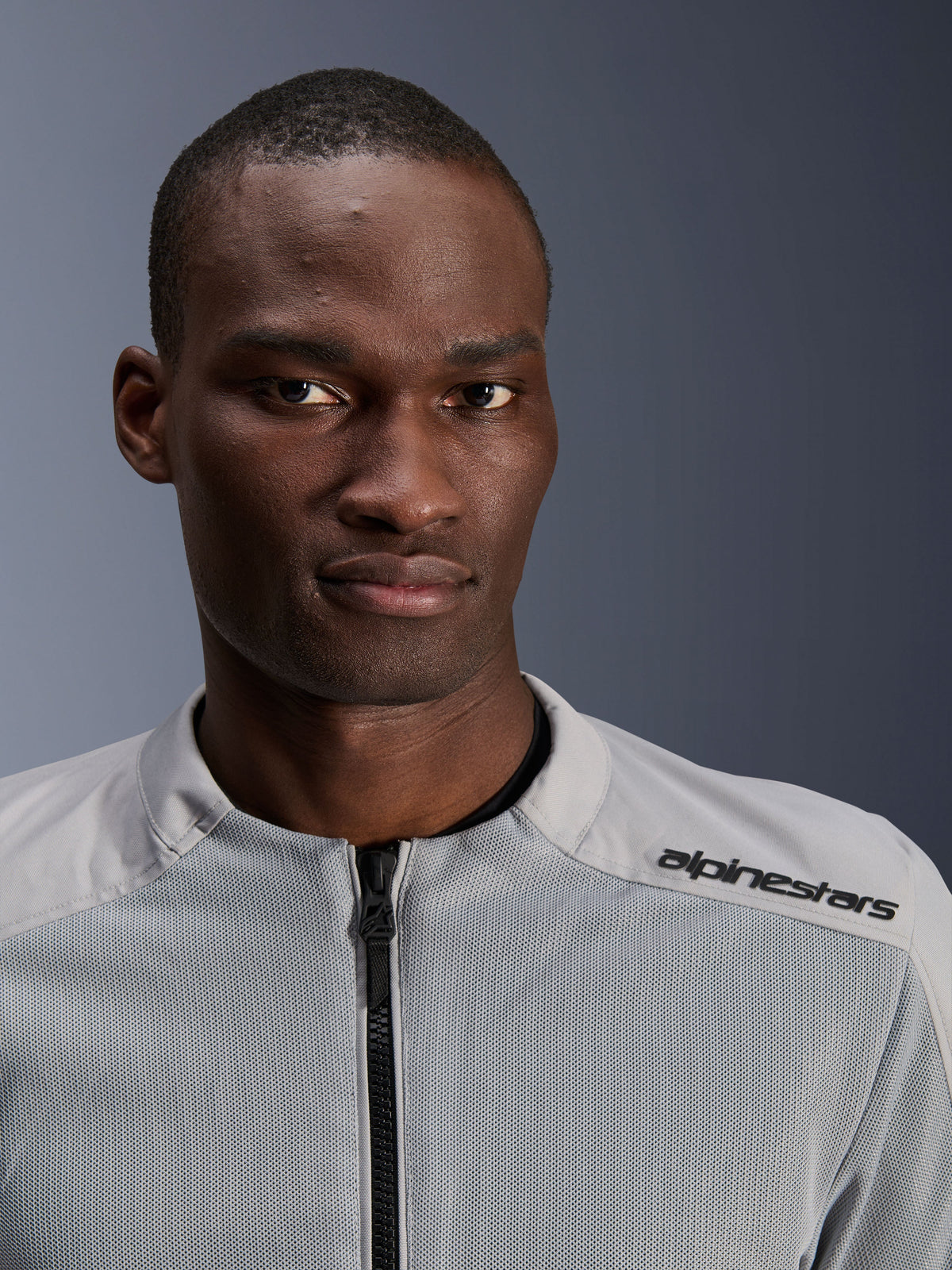 Alpinestars C-1 Air Jacket in argento e grigio, ritratto ravvicinato di un motociclista, con pannelli in rete tecnica e marchio nero sulla spalla, abbigliamento moto urban contemporary
