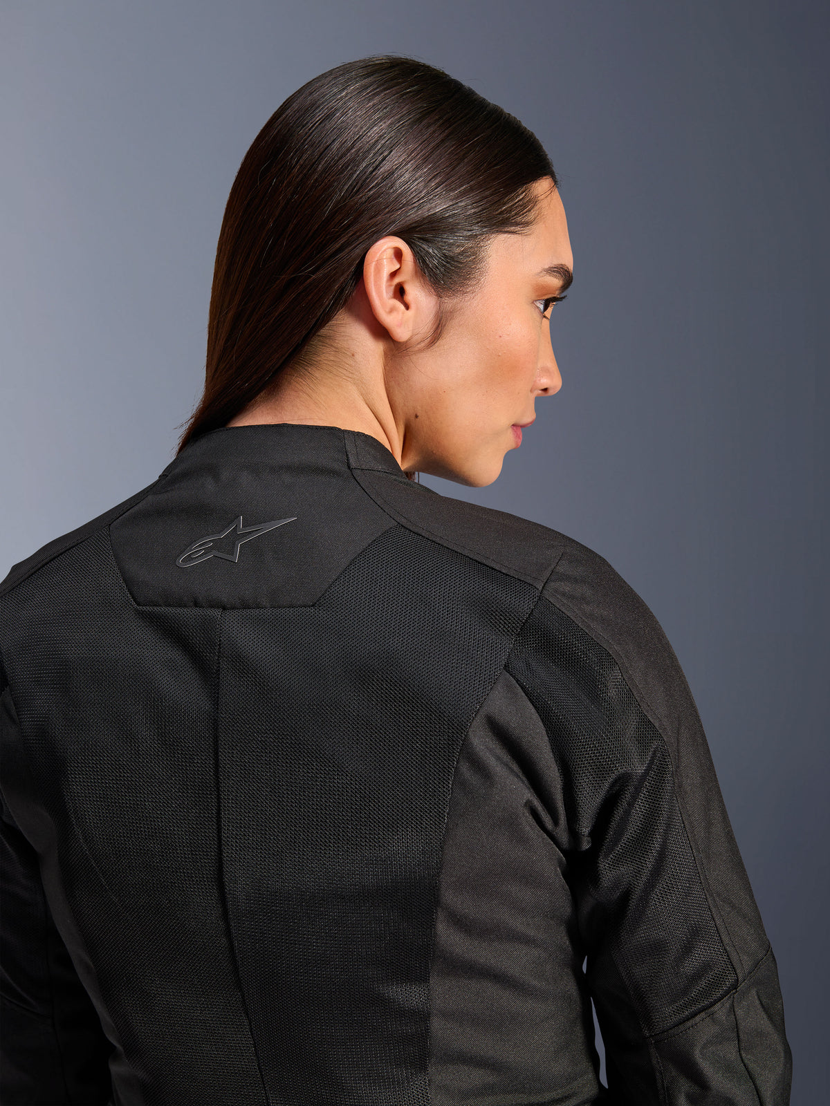 Giacca Alpinestars Stella C-1 Air da donna, giacca da moto in tessuto, nero, vista posteriore ravvicinata che mostra i pannelli di ventilazione in mesh tecnico e un logo a stella riflettente sulla parte superiore della schiena, abbigliamento moderno per la guida urbana