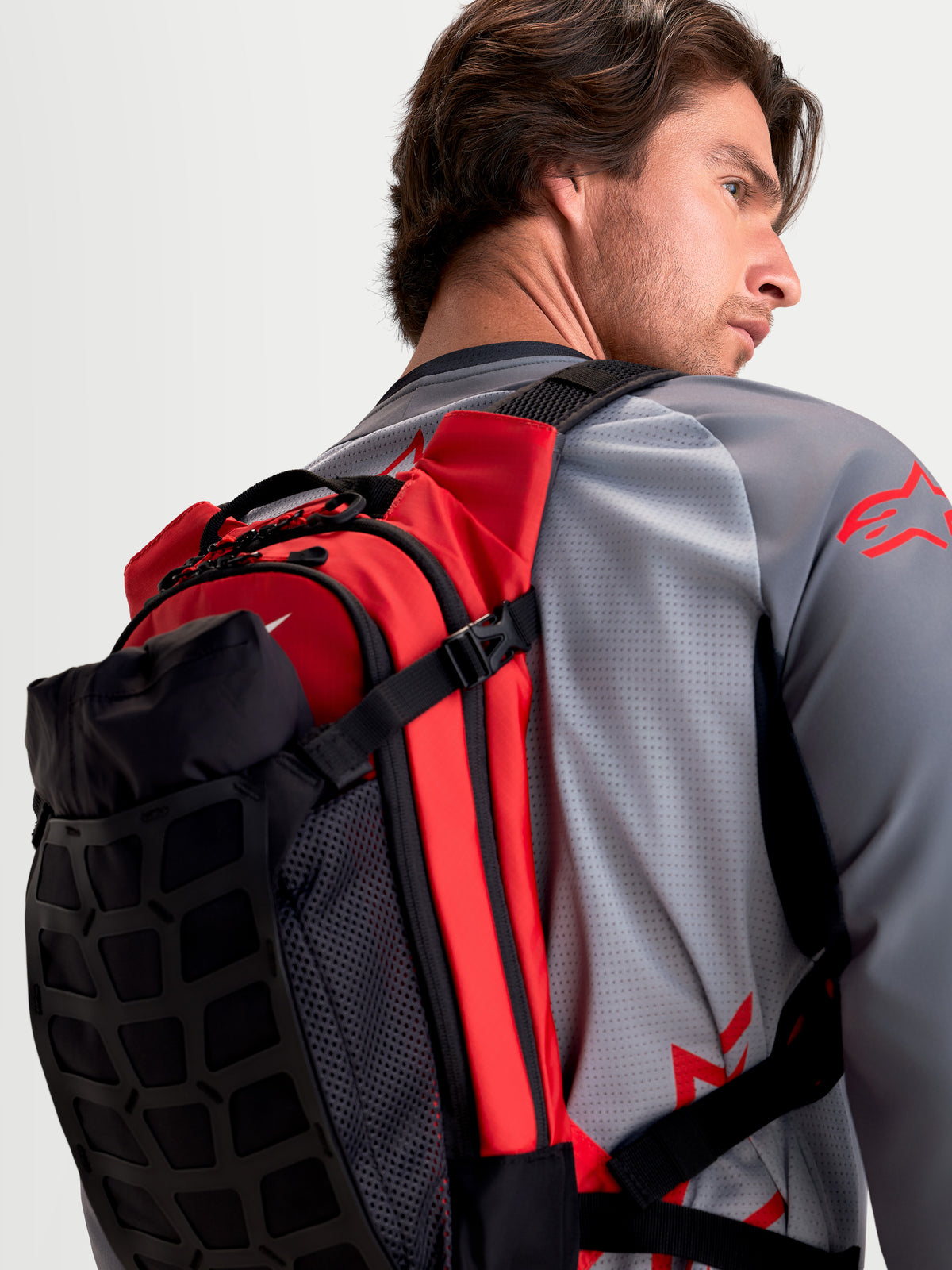 Alpinestars Zaino AT-9, zaino da motocross nero e rosso acceso, vista posteriore indossato da un modello che mostra la costruzione leggera in tessuto e gli spallacci imbottiti
