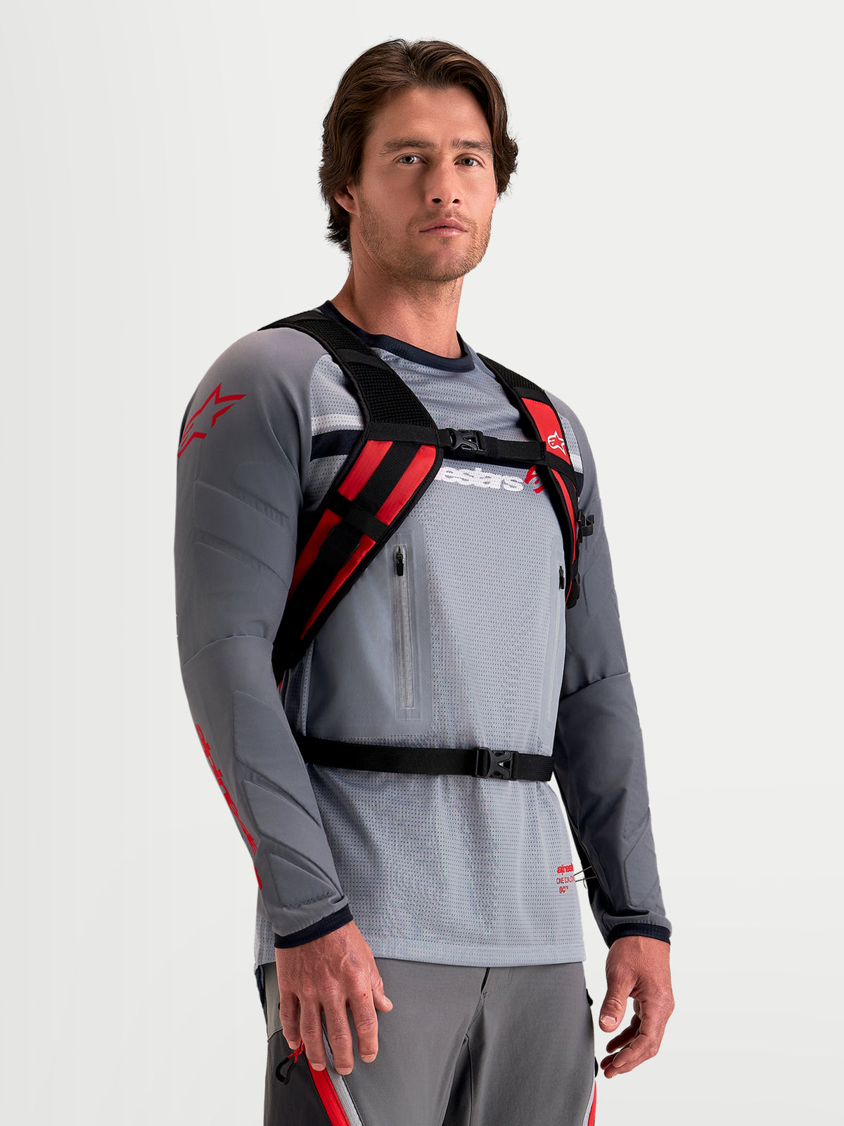 Alpinestars Zaino AT-9, zaino da motocross nero e rosso acceso, indossato da un modello che mostra il sistema di imbracatura imbottito e la chiusura sicura