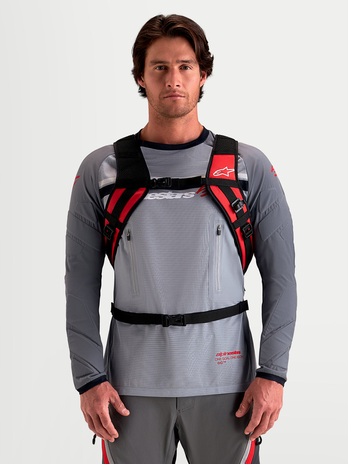 Alpinestars Zaino AT-9, zaino da motocross indossato da un modello, nero e rosso acceso con spallacci imbottiti e sistema di imbracatura, struttura in tessuto leggero