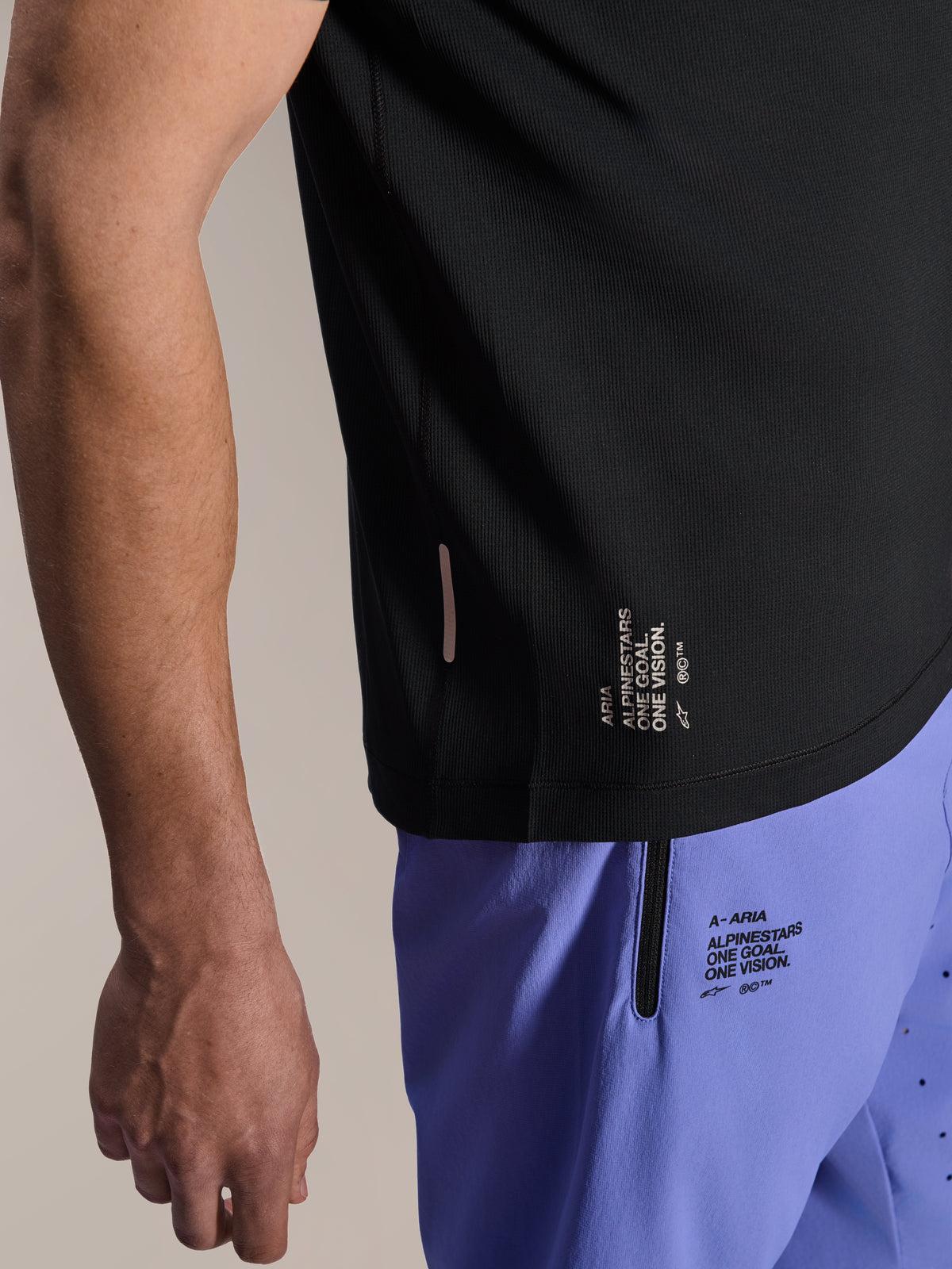 Alpinestars A-Aria Lite Short in Baja Blue, pantaloncini da MTB con marchio 'One Goal. One Vision.' stampato e tasca con zip, abbinati a una maglia A-Aria Switch nera, primo piano di abbigliamento tecnico da ciclismo.