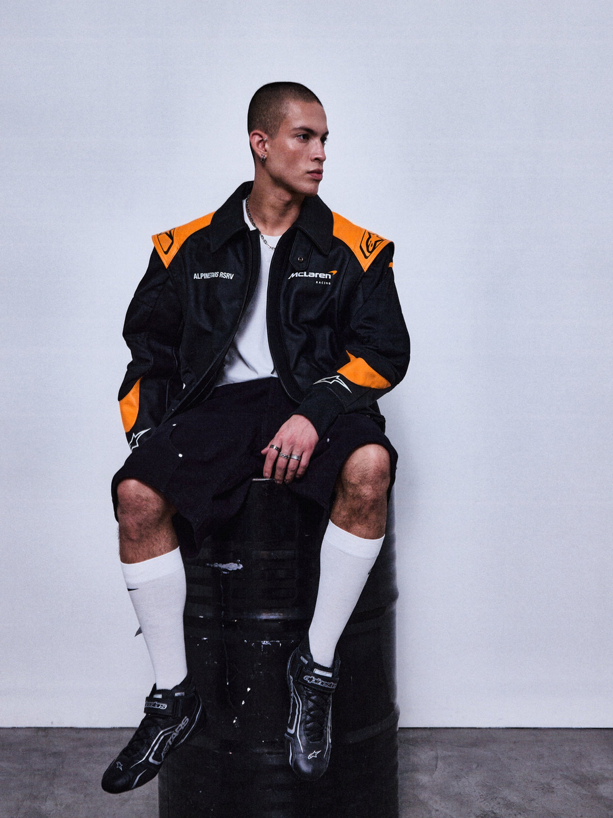 Alpinestars RSRV Track Star Leather Jacket, giacca in pelle nera e arancione, stile sportivo casual, indossata con pantaloncini neri e calzini bianchi