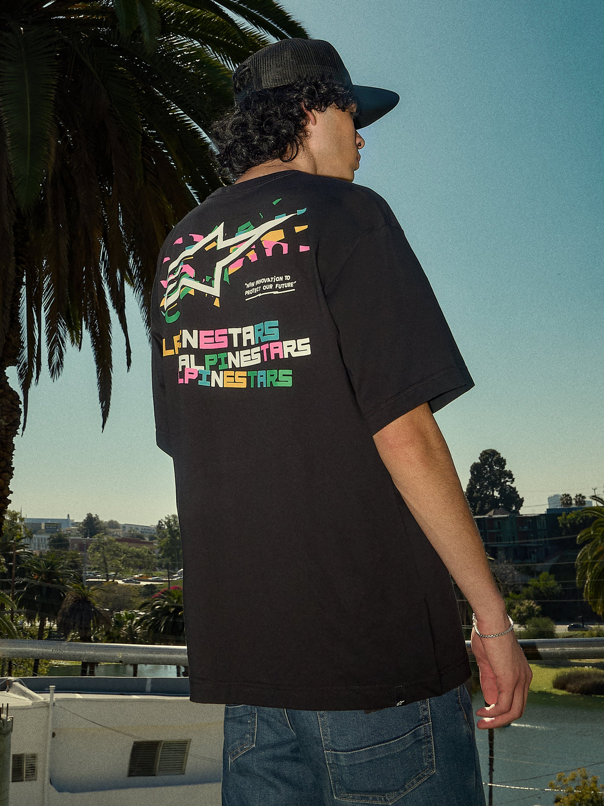 Alpinestars Wild Oversized CSF Tee, t-shirt a maniche corte, nero, logo Astars multicolore vivace sul retro, vestibilità oversize, scatto lifestyle streetwear casual con palme