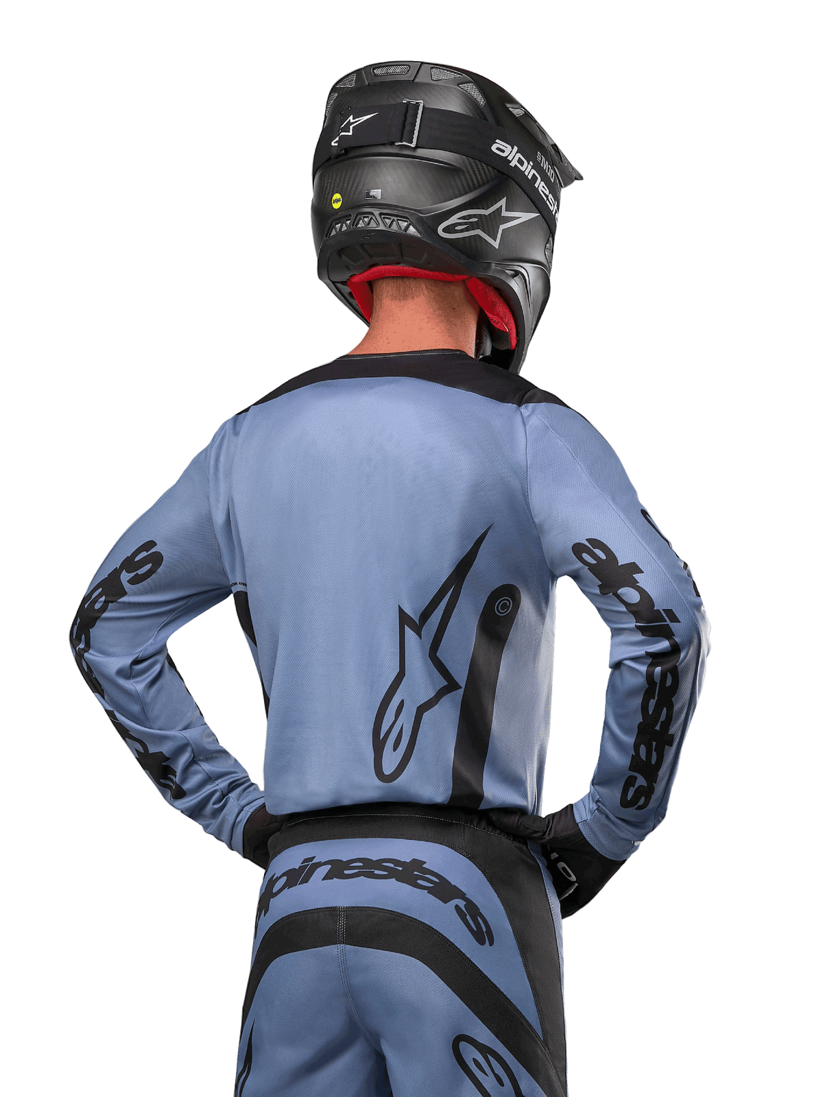 Alpinestars 2024 Fluid Lurv Jersey, maglia da motocross, azzurro e nero, vista posteriore del pilota che mostra il grande logo a stella e il branding sulle maniche, indossata con casco nero e pantaloni da fuoristrada coordinati, abbigliamento racing professionale