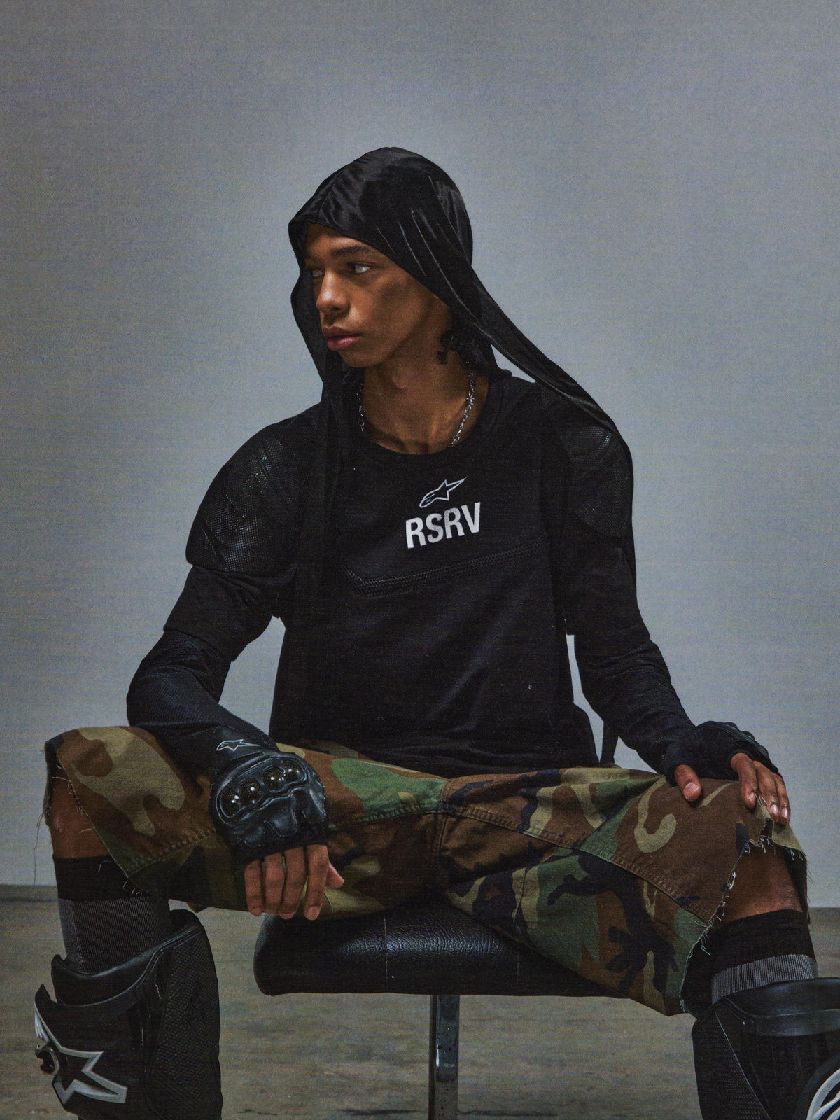 Alpinestars RSRV Nucleon SS Tee, t-shirt nera con logo RSRV bianco, stile streetwear urbano, indossata con pantaloni mimetici e protezioni
