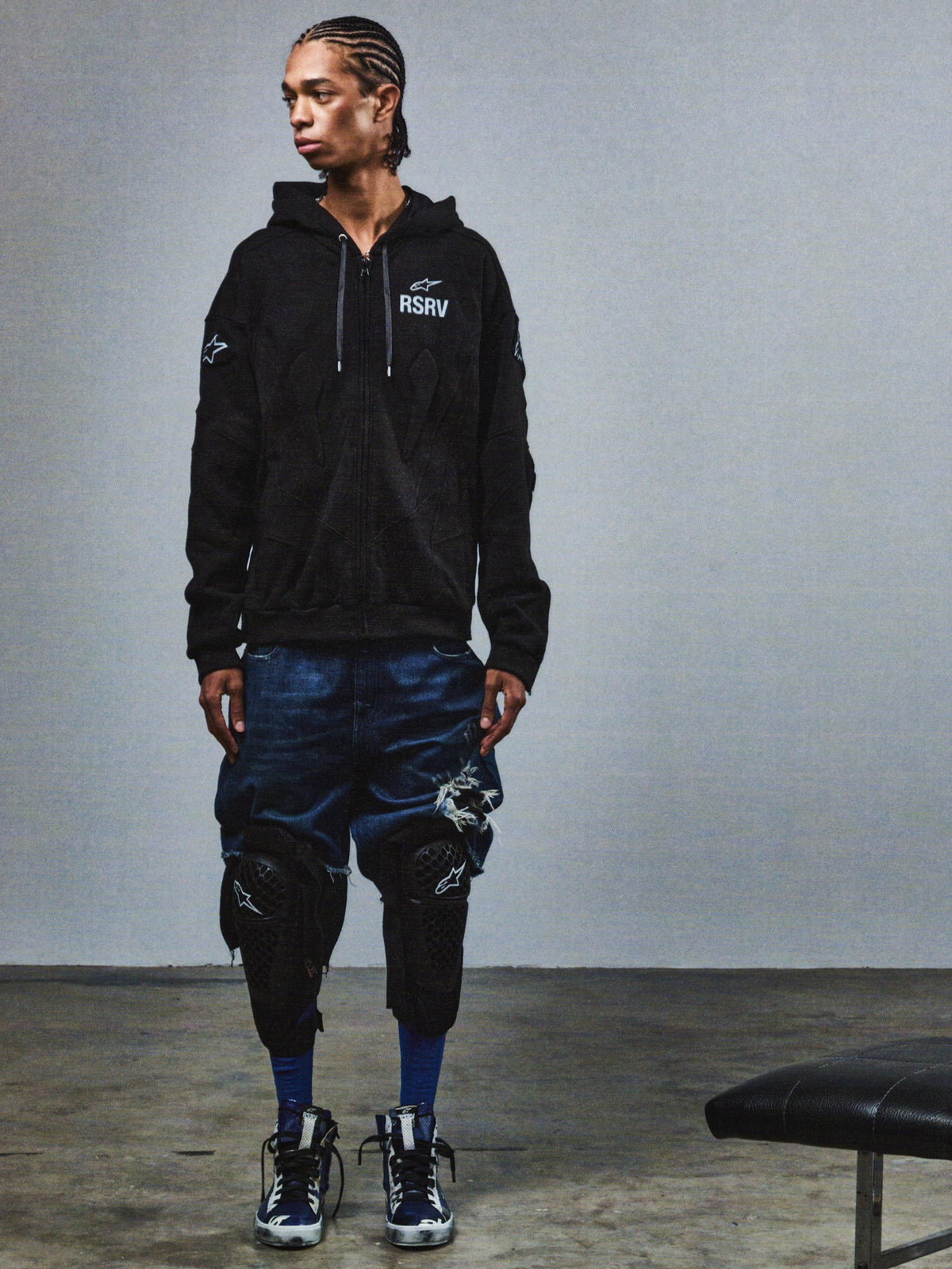 Alpinestars RSRV GP Hoodie, felpa nera con logo RSRV, abbigliamento streetwear premium, stile urbano casual, indossata con shorts denim e ginocchiere