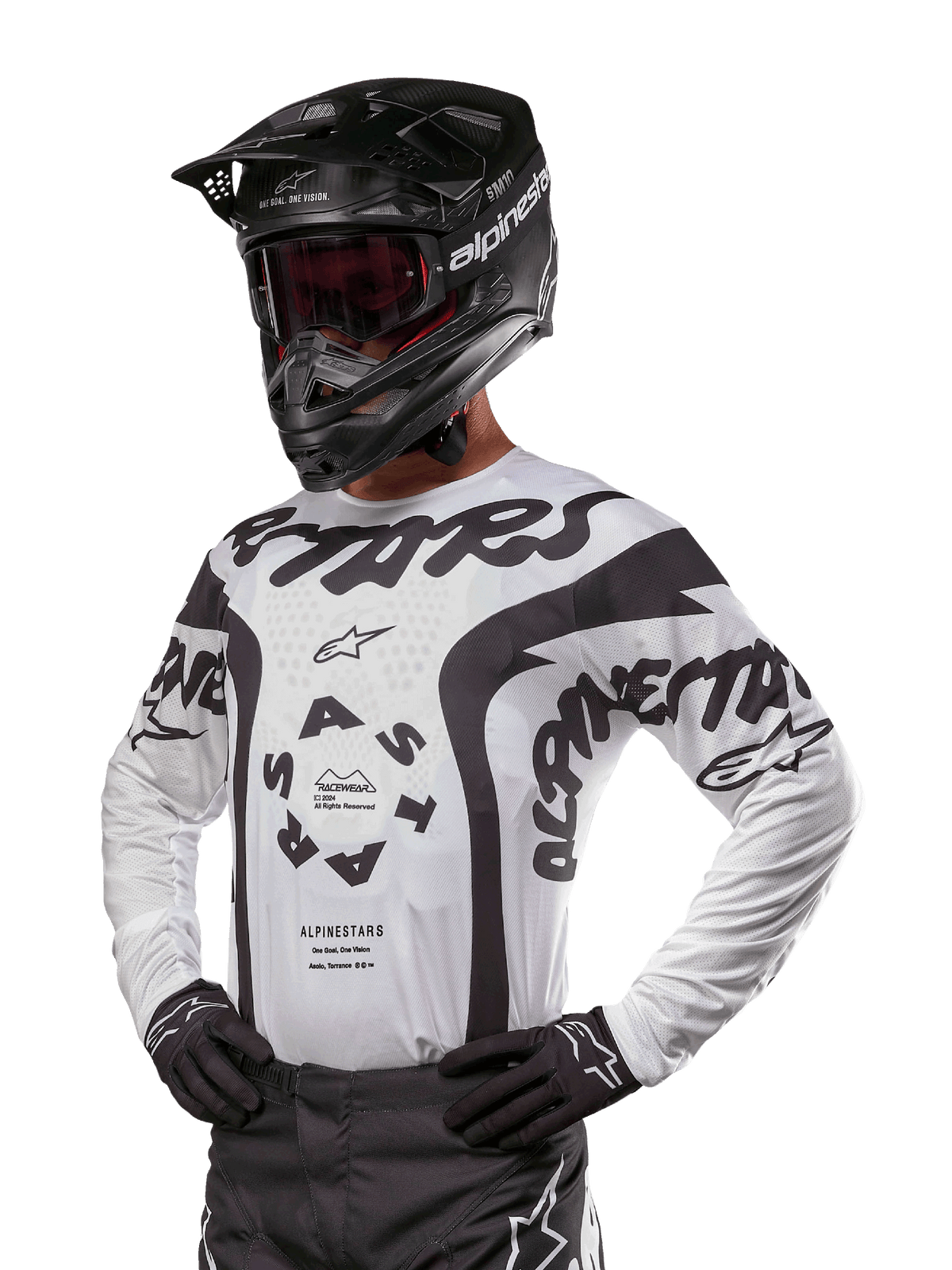 Alpinestars 2024 Racer Hana Jersey, maglia da motocross, bianca e nera, grafiche audaci con branding Alpinestars e Astars, indossata con casco nero e guanti neri, equipaggiamento tecnico da motocross fuoristrada