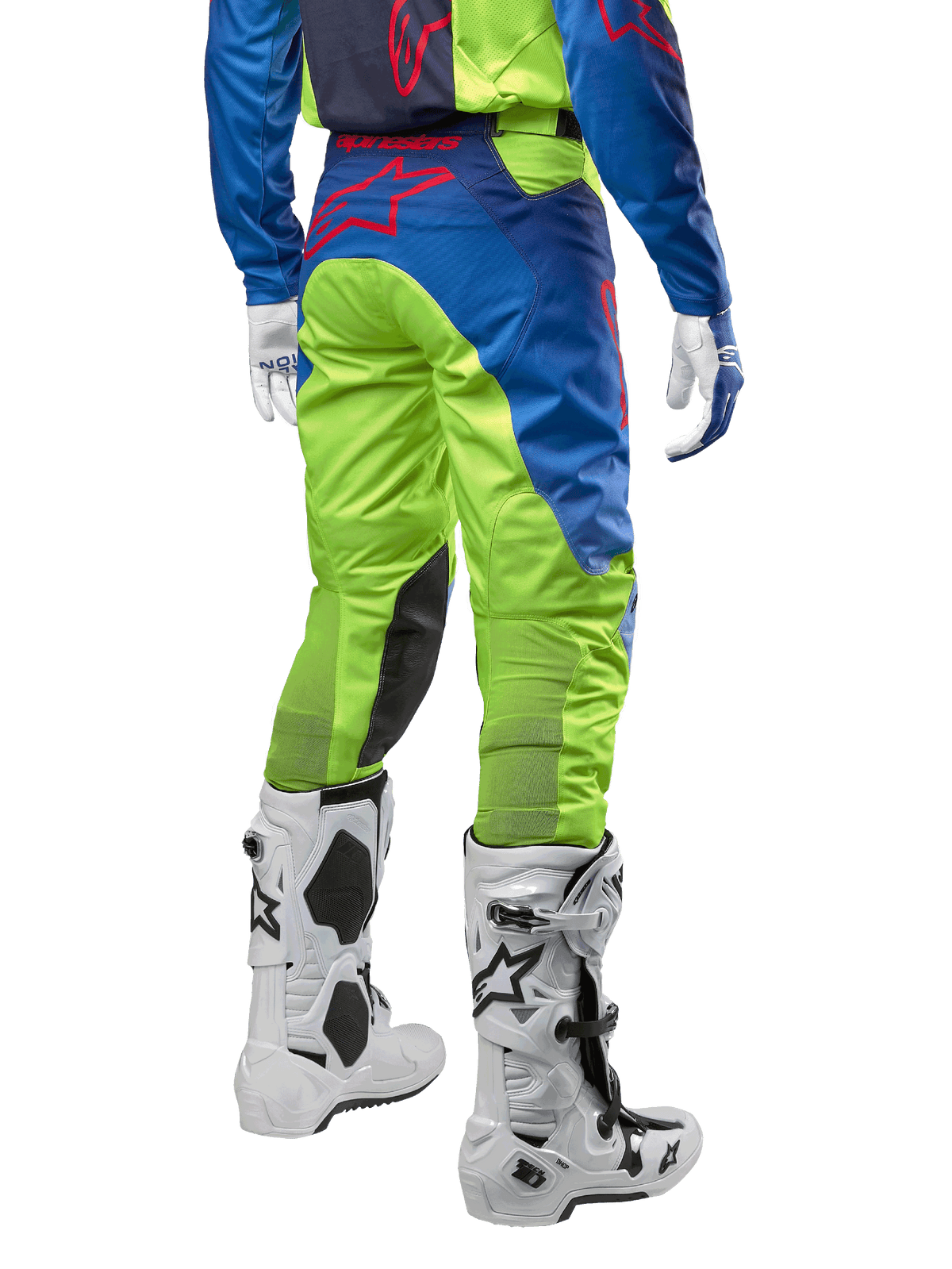 Pantaloni Alpinestars Racer Hoen 2024, pantaloni da motocross, giallo fluo e blu Night Navy, vista posteriore, con logo Alpinestars rosso, indossati con maglia coordinata, guanti bianchi e stivali da motocross bianchi, tessuto resistente per corse off-road