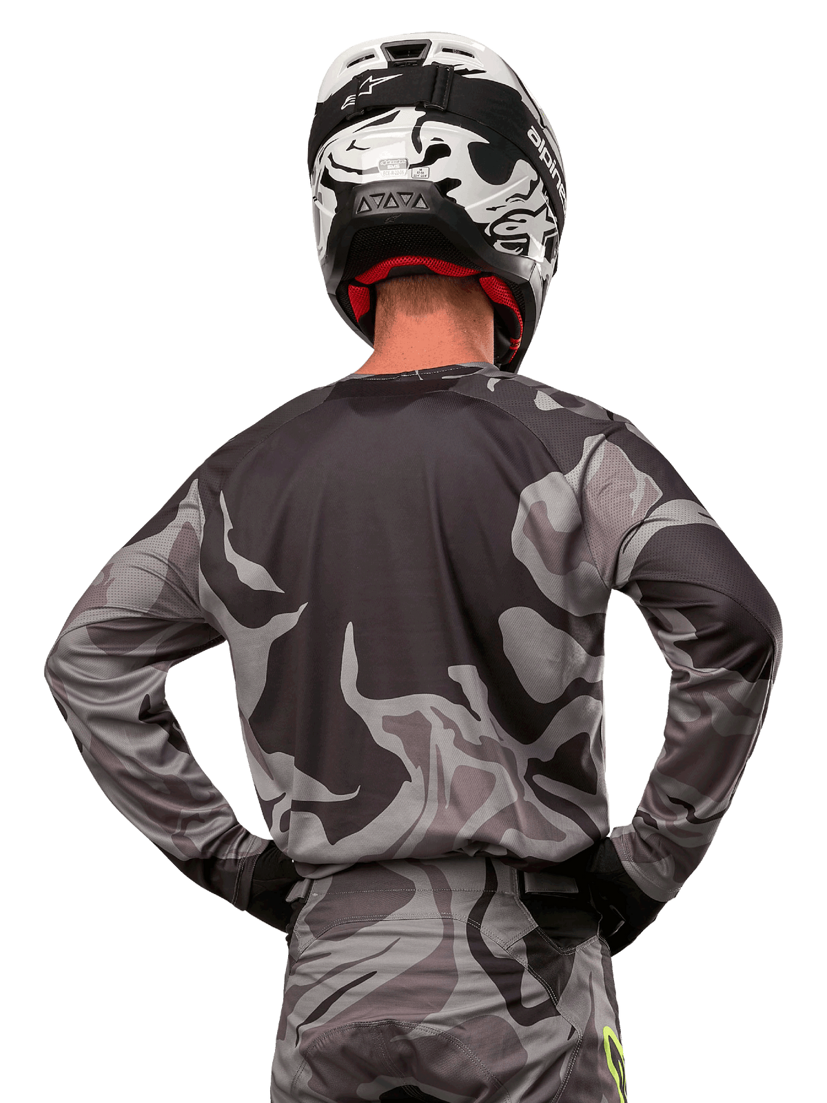 Alpinestars Racer Tactical Jersey 2024, maglia da motocross, Cast Gray Camo Magnet, vista posteriore con motivo mimetico grigio e nero, indossata con pantaloni coordinati e casco bianco e nero, abbigliamento professionale per corse fuoristrada