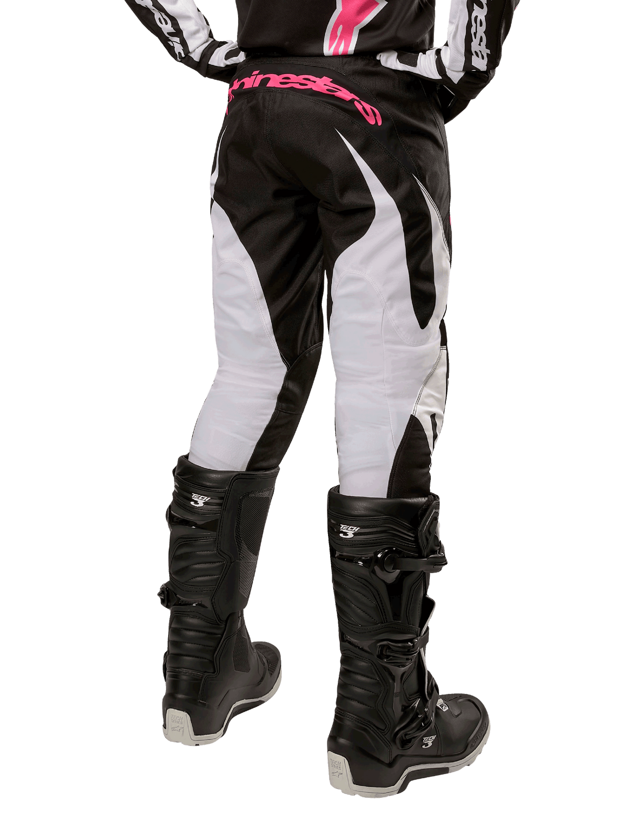 Alpinestars Stella Fluid Pant 2024 da donna, pantaloni da motocross, nero e bianco, vista posteriore che mostra pannelli bianchi sulle gambe e logo rosa sulla fascia in vita, indossati con stivali Tech 3 neri, equipaggiamento resistente per gare fuoristrada