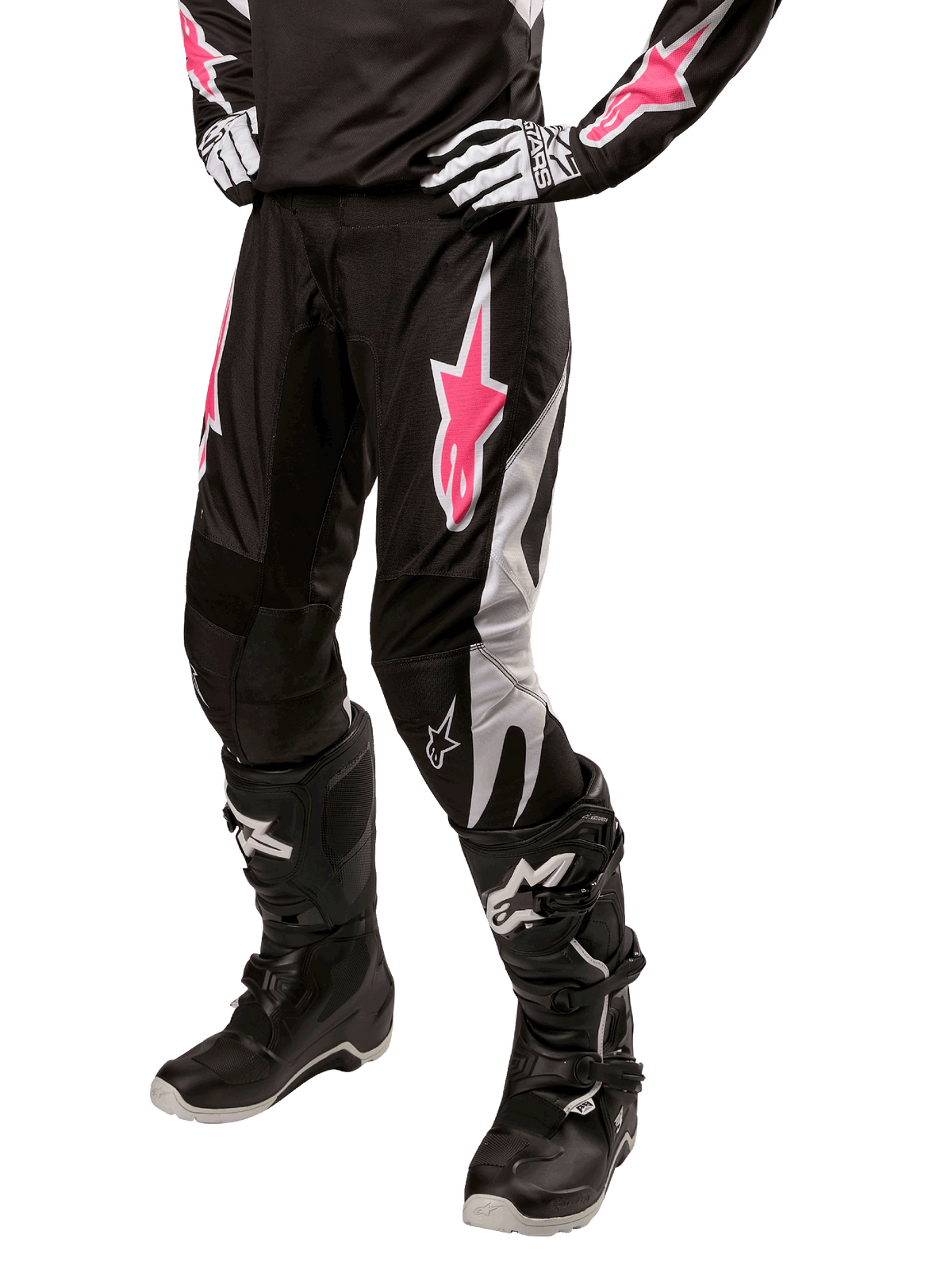 Alpinestars Stella Fluid Pant 2024 da donna, pantaloni da motocross, nero e bianco con dettagli rosa, indossati con attrezzatura protettiva coordinata inclusi stivali e guanti, tessuto resistente e flessibile per la guida fuoristrada
