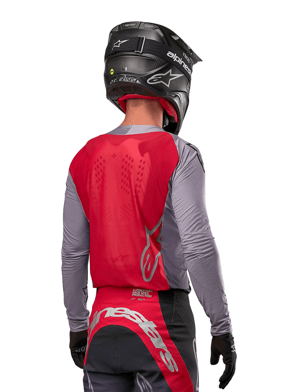 Pilota di motocross visto da dietro che indossa la maglia Alpinestars Supertech Dade 2024 in Iron Red Berry e grigio, con pannello posteriore in mesh traspirante e dettagli del logo in argento, abbinata a un casco nero e pantaloni da corsa coordinati per prestazioni off-road professionali.