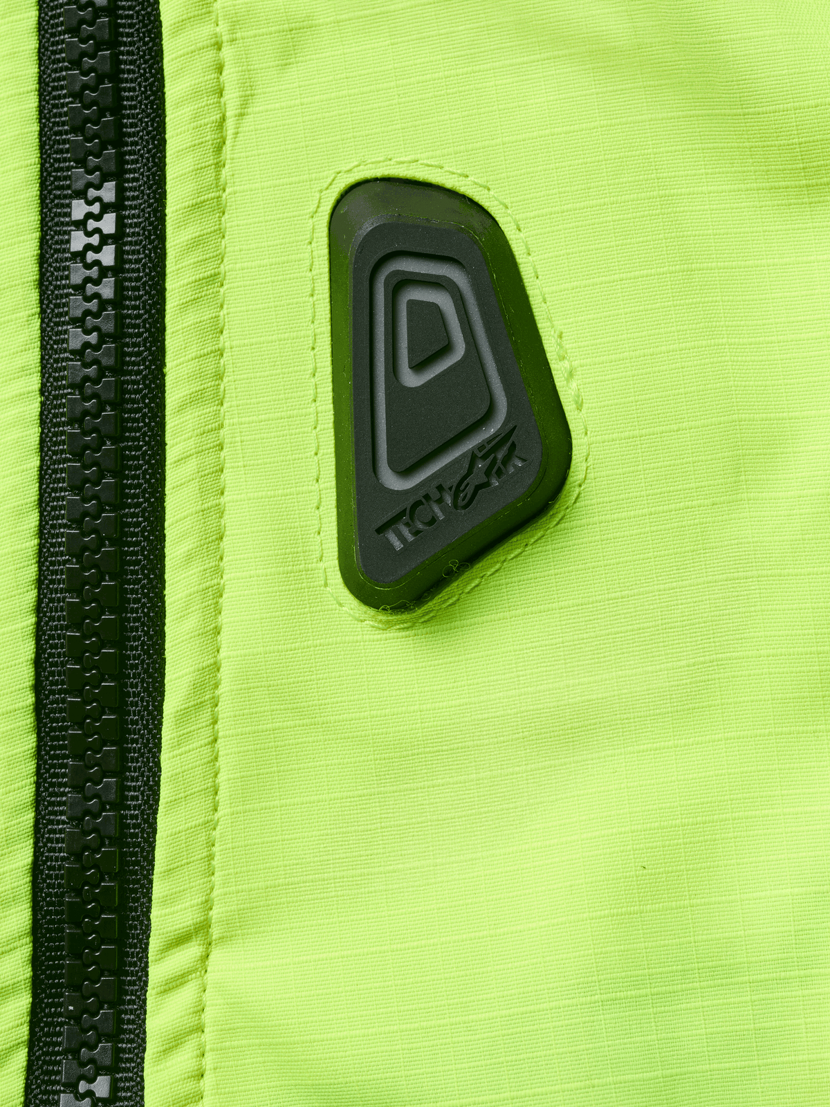 Alpinestars Tech-Air® 3 V2 System, gilet airbag da moto, primo piano del tessuto giallo fluo resistente all'acqua con cerniera nera, con patch gommata nera del logo Tech-Air, dispositivo di sicurezza ad alta visibilità
