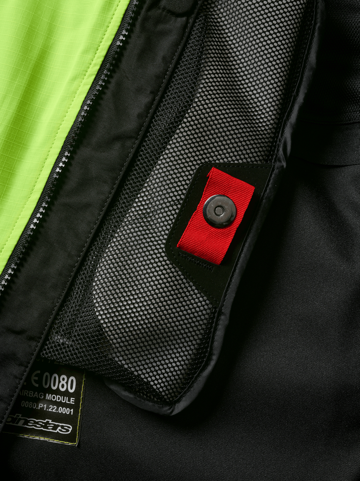 Dettaglio del sistema Alpinestars Tech-Air® 3 V2, primo piano della tasca interna in rete con linguetta rossa e chiusura a scatto, pannello giallo fluo vivace, struttura in tessuto nero con etichetta del modulo airbag e cerniera