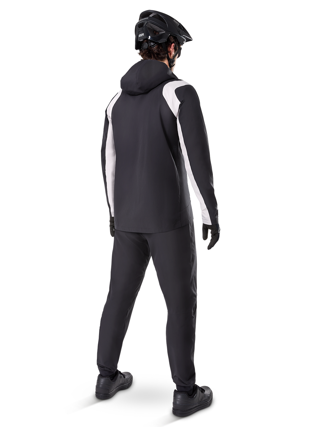 Alpinestars Giacca Antipioggia A-Dura, vista posteriore di un ciclista che indossa la giacca da MTB impermeabile bianca e nera, pantaloni da ciclismo neri coordinati, casco e guanti neri, equipaggiamento tecnico per mountain bike in condizioni di pioggia