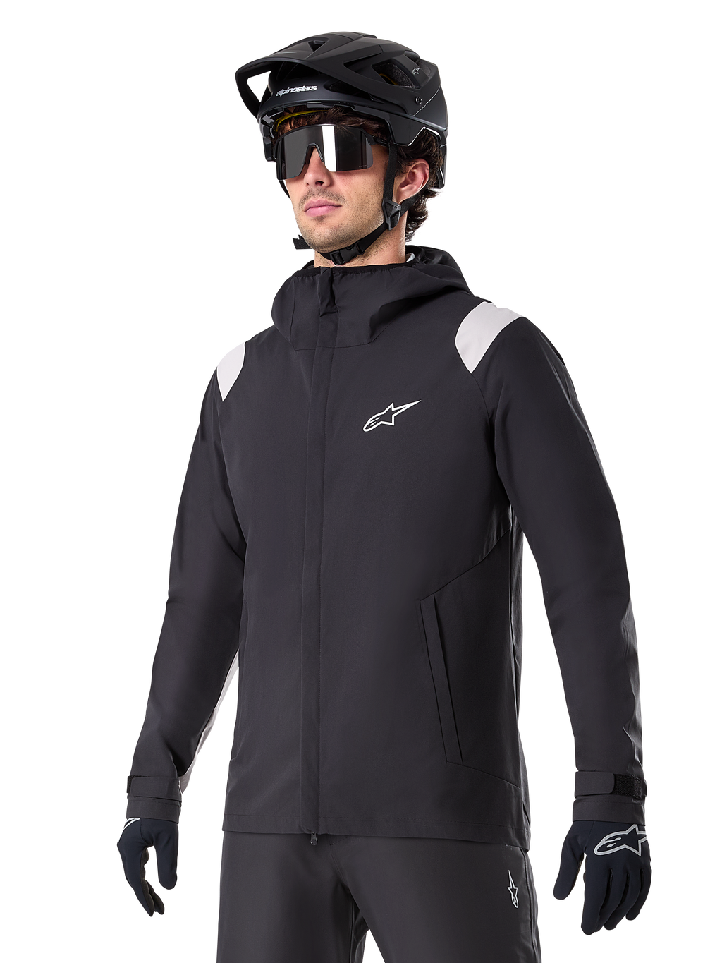 Alpinestars A-Dura Rain Jacket, giacca antipioggia da mountain bike, nera con inserti grigio chiaro sulle spalle, indossata da un ciclista con casco da MTB nero e occhiali da sole, logo bianco sul petto, costruzione impermeabile, coordinata con pantaloni e guanti neri per ciclismo fuoristrada