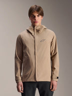 Alpinestars A-Dura Rain Jacket, giacca antipioggia da mountain bike con cappuccio, marrone chiaro, indossata da un modello, con piccolo logo sul petto, polsini regolabili e cerniera frontale nascosta, abbigliamento impermeabile per ciclismo