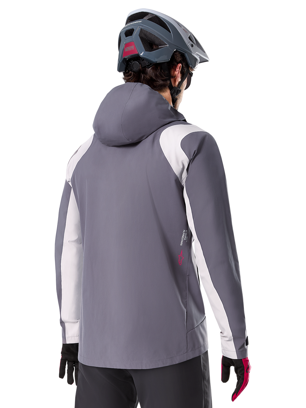Alpinestars Giacca Antipioggia A-Dura, giacca da mountain bike, grigio titanio scuro, vista posteriore con pannelli su spalle e braccia grigio chiaro, dettaglio logo rosso sul lato, indossata con casco MTB grigio e guanti neri e rossi, abbigliamento tecnico da trail riding