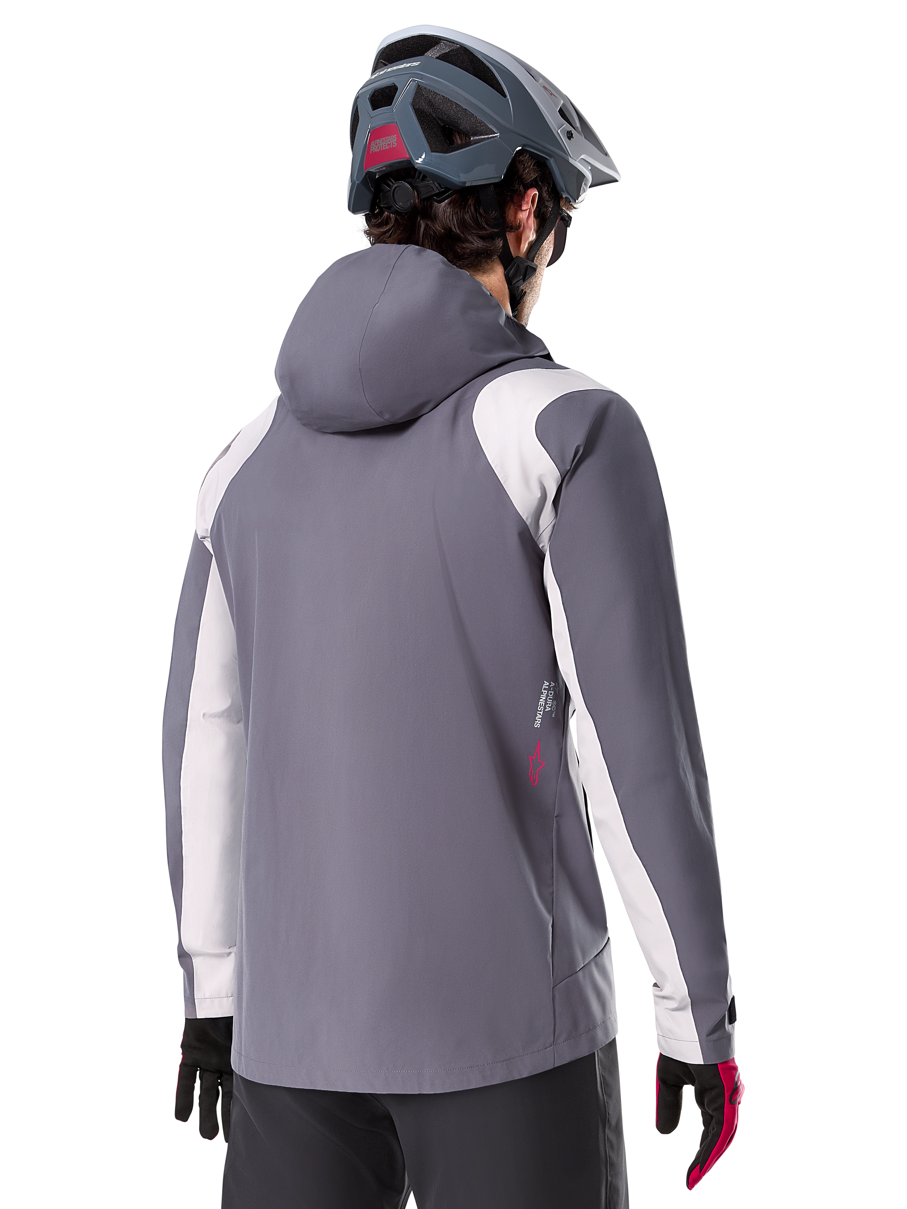 Alpinestars Giacca Antipioggia A-Dura, giacca da mountain bike, grigio titanio scuro, vista posteriore con pannelli su spalle e braccia grigio chiaro, dettaglio logo rosso sul lato, indossata con casco MTB grigio e guanti neri e rossi, abbigliamento tecnico da trail riding