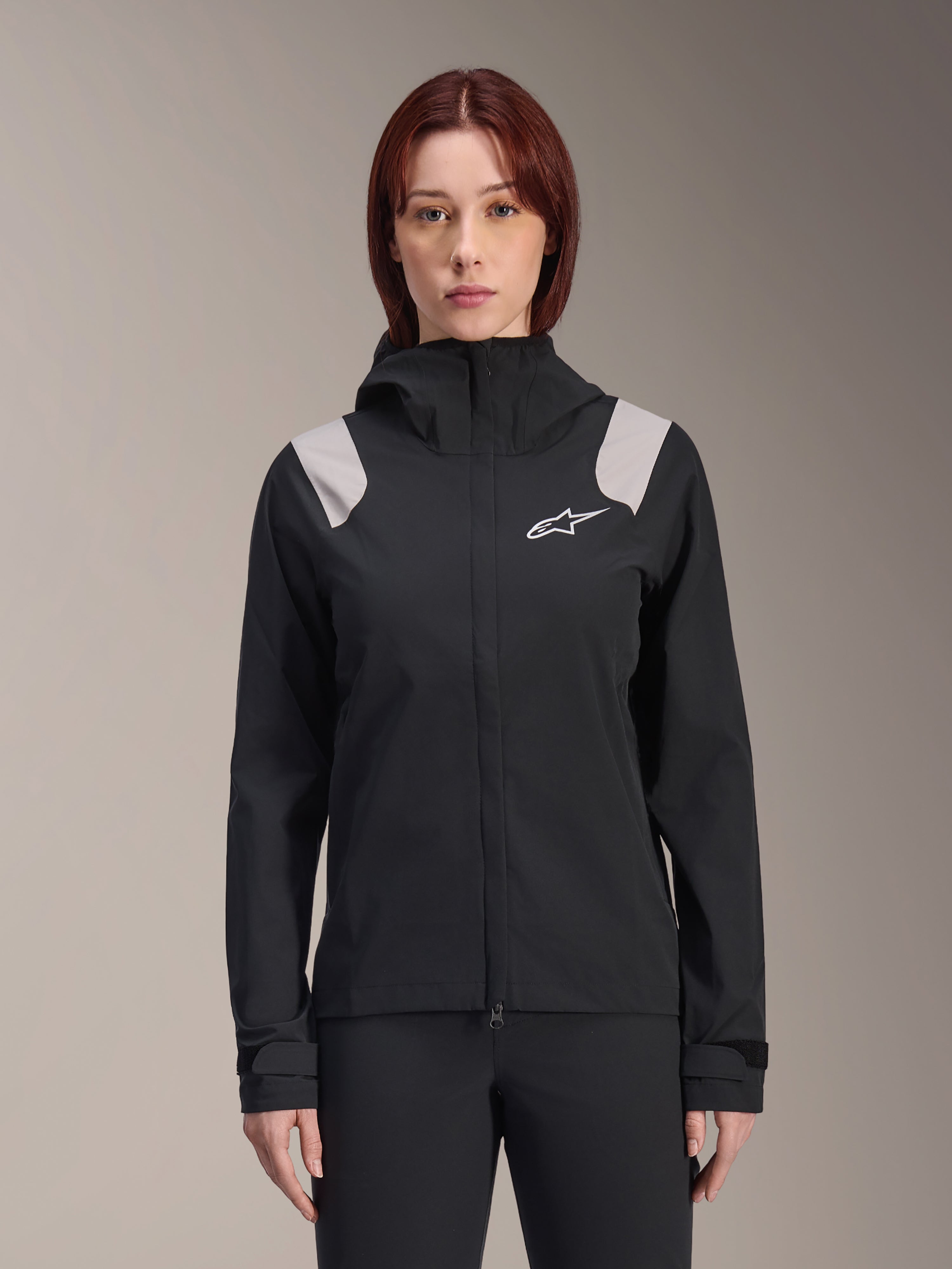 Alpinestars Stella A-Dura Rain Jacket, giacca antipioggia da ciclismo da donna, nera con pannelli grigi chiari sulle spalle, guscio tecnico con cappuccio e logo bianco sul petto, polsini regolabili in velcro, equipaggiamento professionale per MTB e guida sotto la pioggia