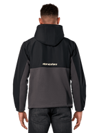 Giacca Alpinestars Juncture Hybrid, vista posteriore, Nero e Gunmetal, anorak casual sportswear con costruzione in materiali misti, parte superiore in ripstop e parte inferiore in pile di tela, logo Alpinestars sul retro, indossata con pantaloni scuri