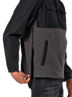 Giacca Alpinestars Juncture Hybrid in Black Gunmetal, vista laterale del dettaglio che evidenzia la cerniera laterale e la tasca inferiore a filetto, design in materiali misti con pile in tela grigia e sovrapposizioni in ripstop nero, streetwear casual ispirato al motorsport