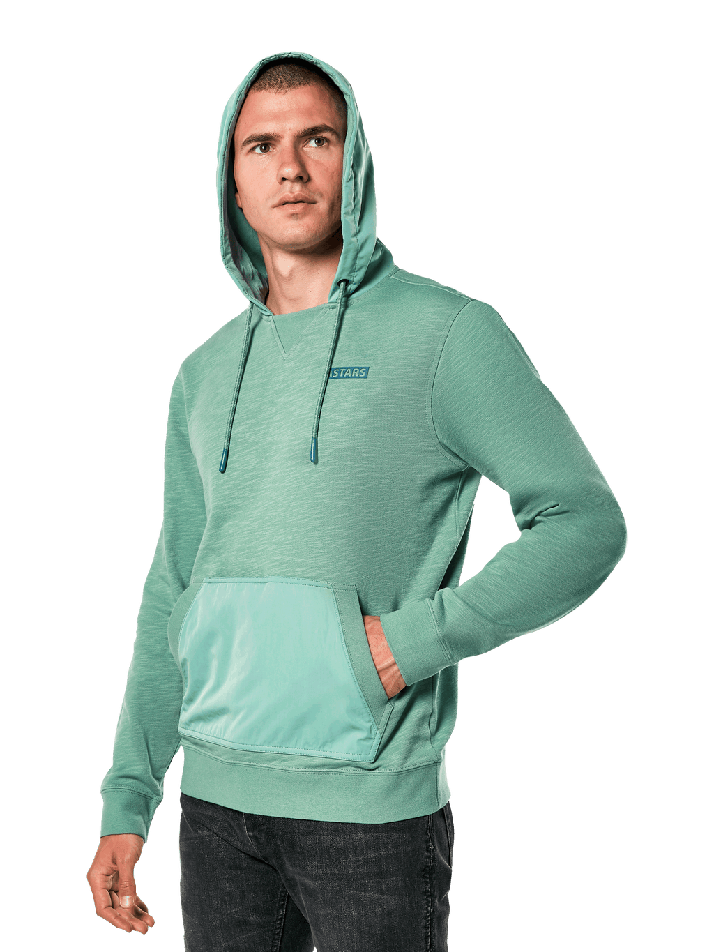 Alpinestars Rooted Hoodie, felpa in terry francese slub verde con cappuccio sovrapposto e tasca a marsupio, piccolo logo STARS sul petto, indossata da un modello con cappuccio alzato e mano in tasca, streetwear casual ispirato al motorsport