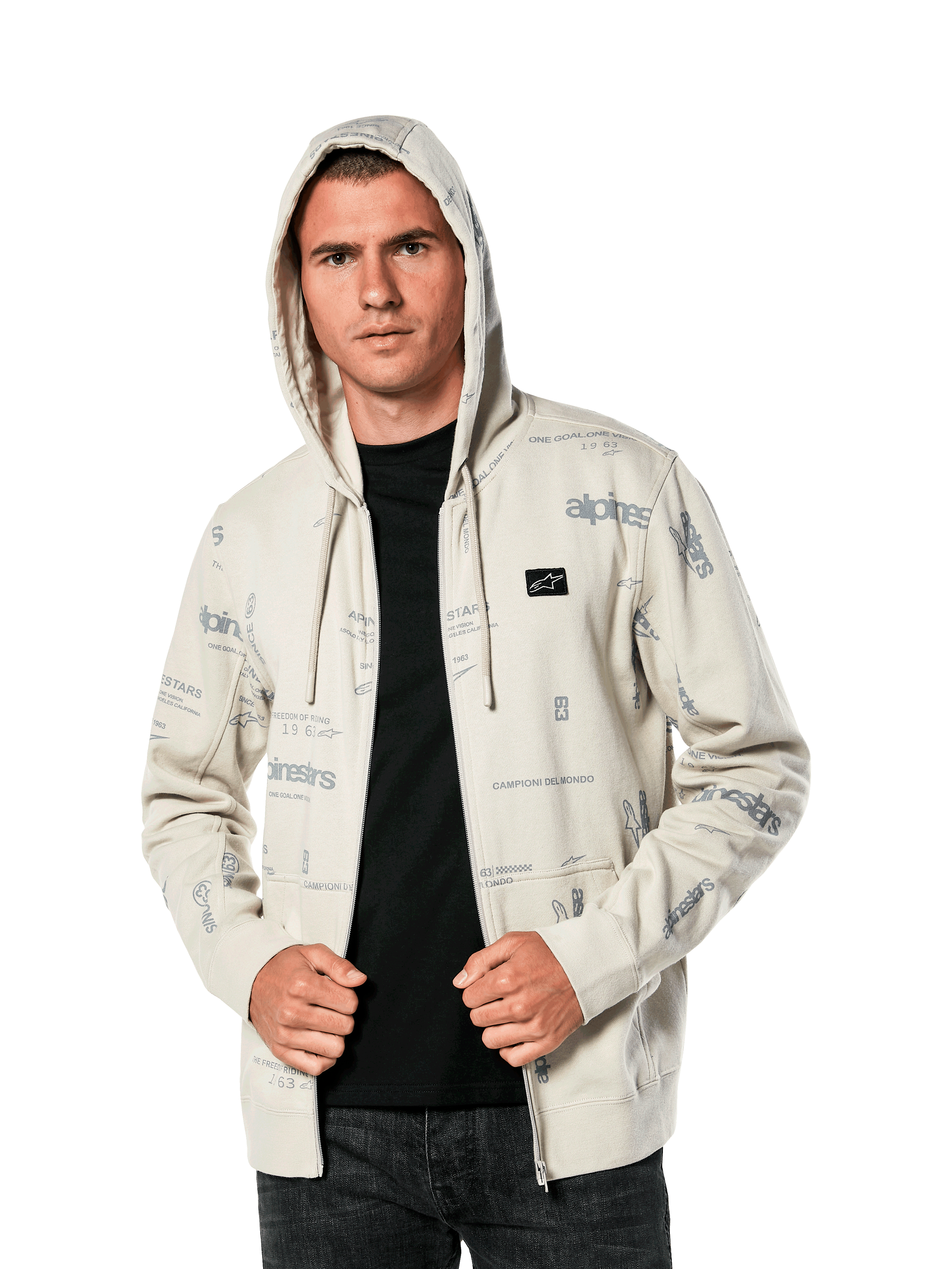 Felpa con cappuccio Alpinestars Plenitude, abbigliamento sportivo casual, felpa Off White con zip frontale e grafiche grigie all-over, indossata da un uomo con il cappuccio alzato sopra una maglia nera, con piccola patch del logo sul petto e tasca a marsupio
