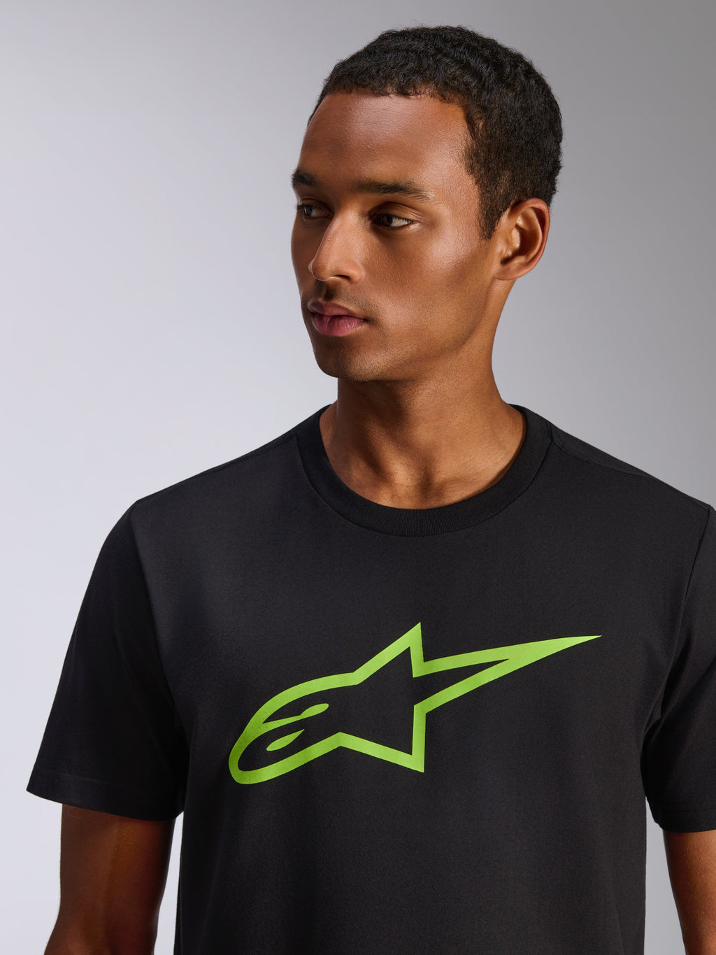 Alpinestars Ageless 2.0 CSF Tee, t-shirt a maniche corte, nera con logo a stella Alpinestars verde lime, indossata da un modello, streetwear casual ispirato al motorsport