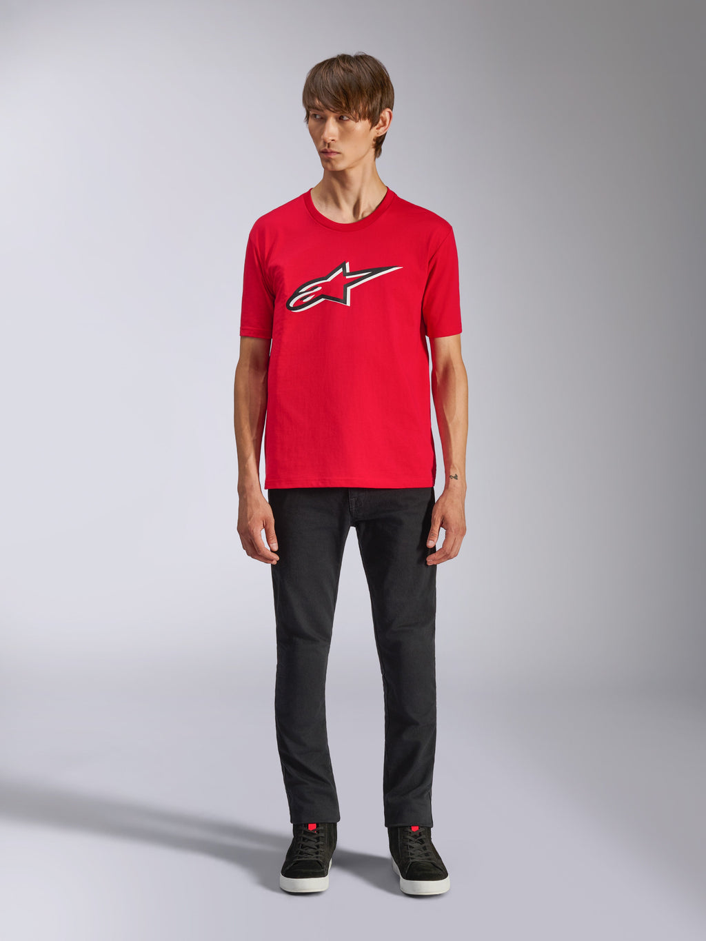 Alpinestars Ageless Shadow CSF Tee, t-shirt a maniche corte, rosso, logo Ageless frontale con contorni bianchi e neri, indossata da un modello con pantaloni neri e sneakers, casual motorsport streetwear