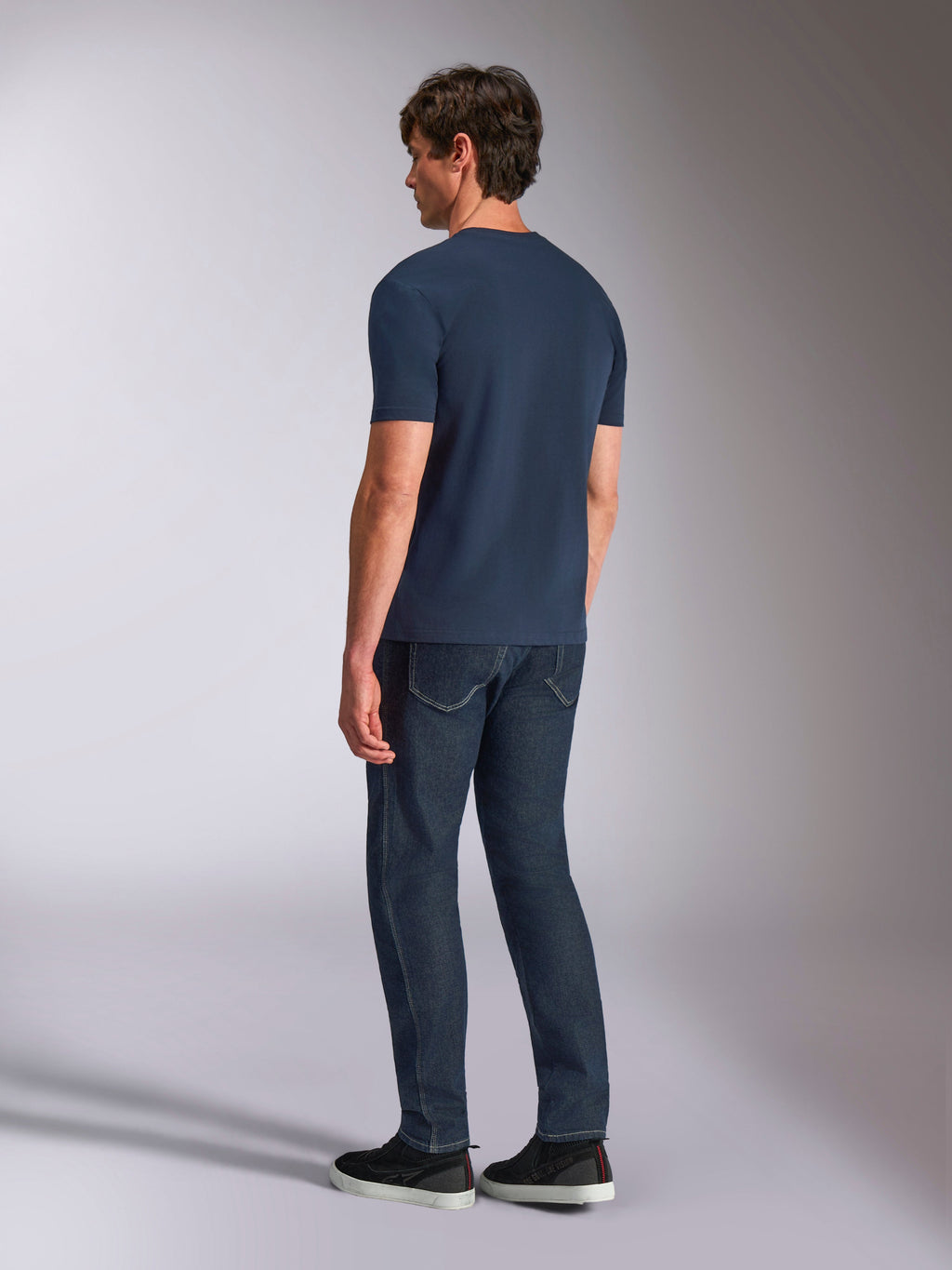 Alpinestars Ageless Shadow CSF Tee, maglietta a maniche corte, navy, vista posteriore su modello, indossata con jeans in denim scuro e sneakers nere, stile casual streetwear